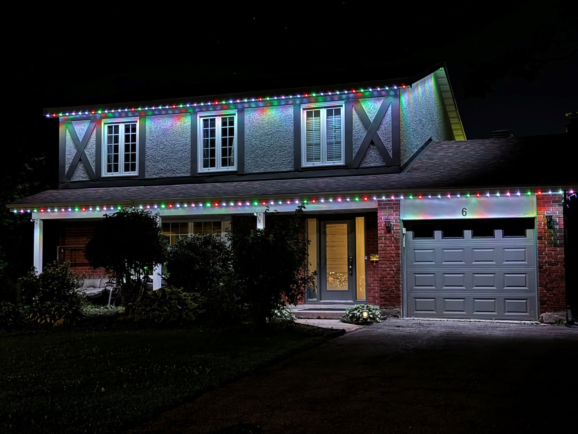 A house with christmas lights on it is lit up at night.