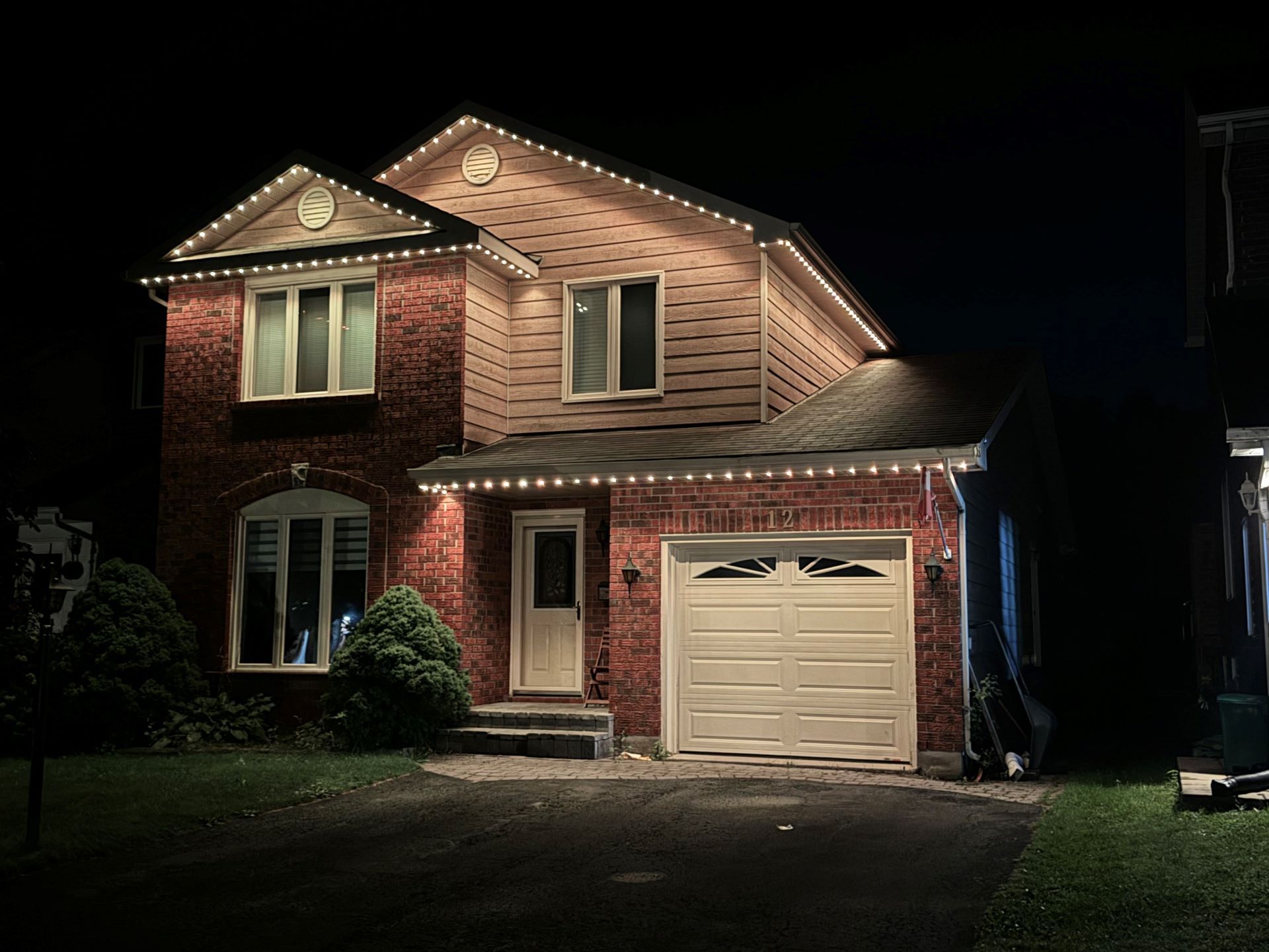 A brick house is lit up at night with christmas lights.