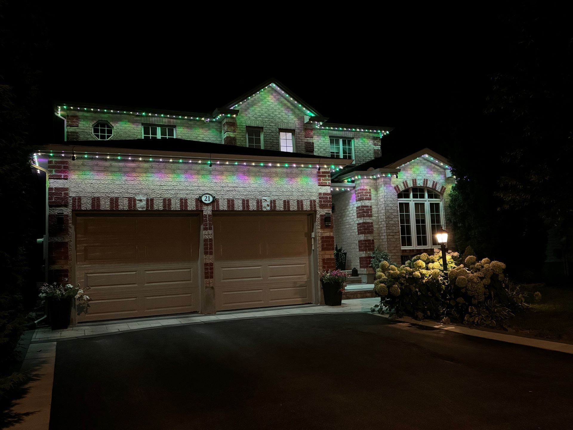 A large house with christmas lights on it is lit up at night.