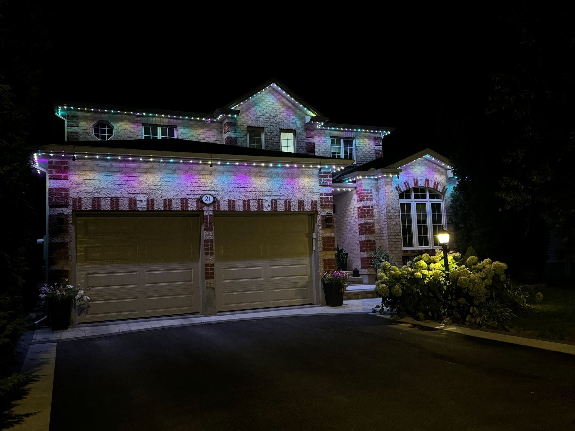 A large house with christmas lights on it is lit up at night.