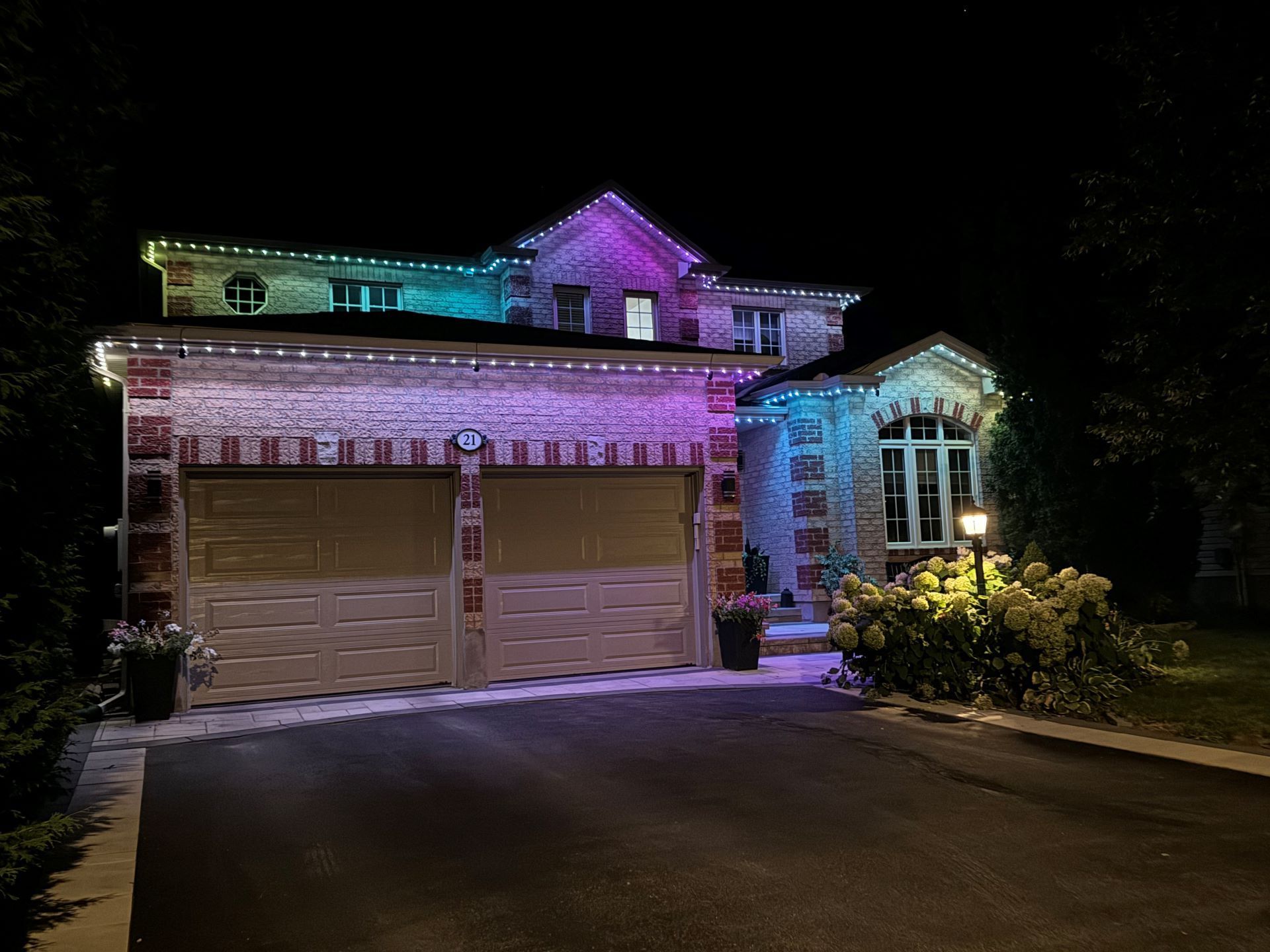 A large house with christmas lights on it is lit up at night.