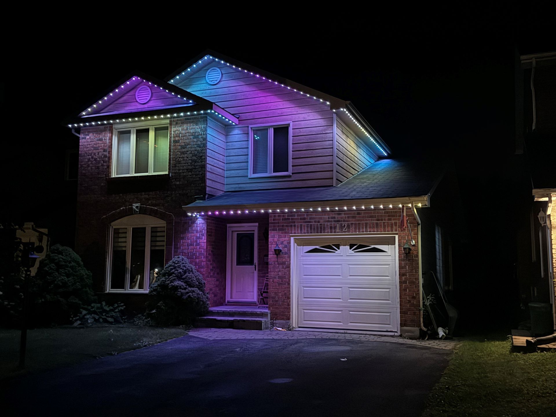 A house with christmas lights on it is lit up at night.