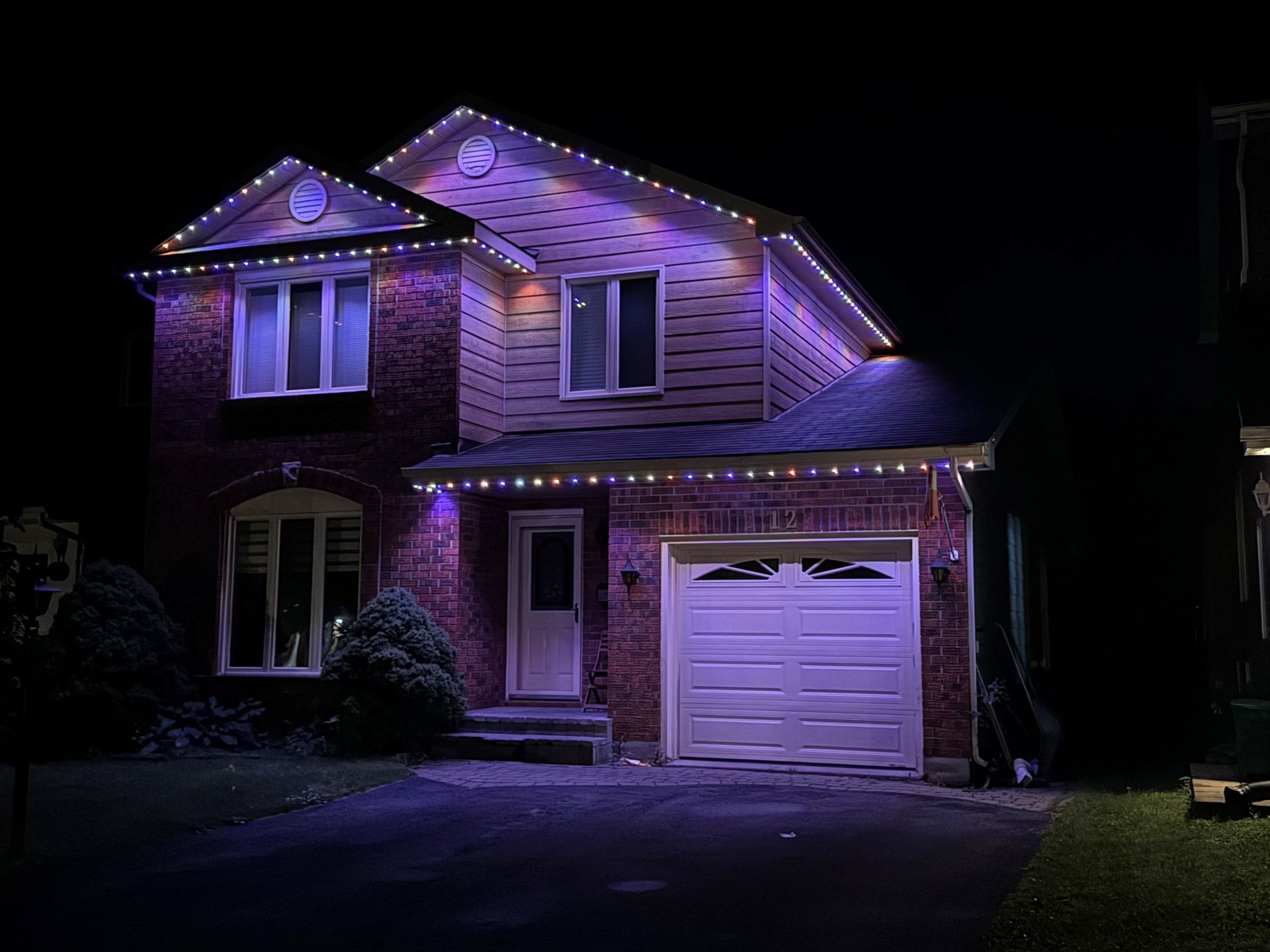 A house with purple lights on it is lit up at night.