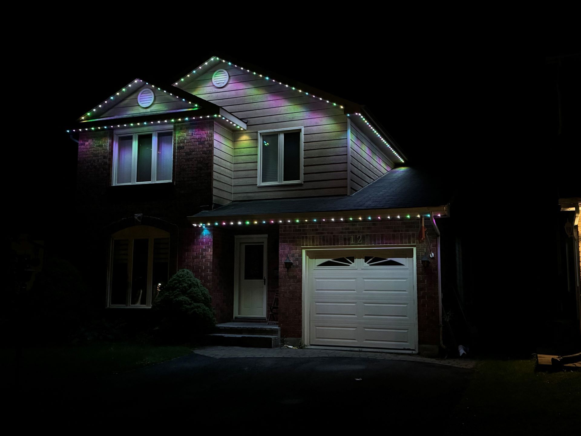 A house with christmas lights on it is lit up at night.