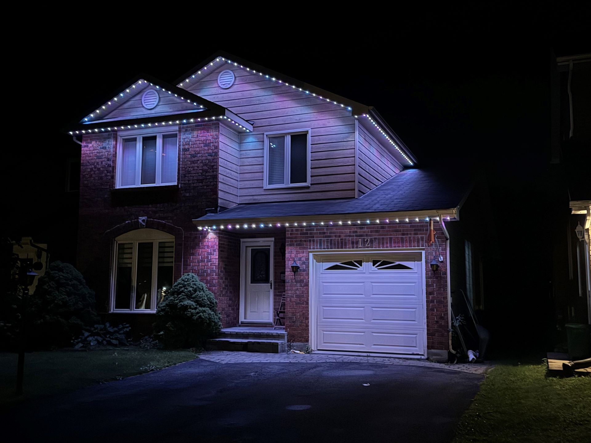 A house with christmas lights on it is lit up at night.