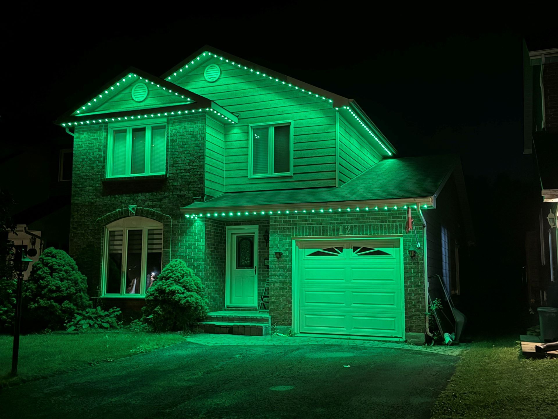 A house is lit up with green lights at night.