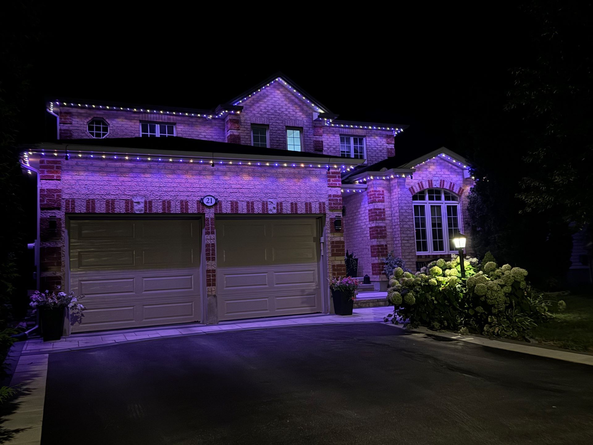 A large brick house is lit up with purple lights at night.