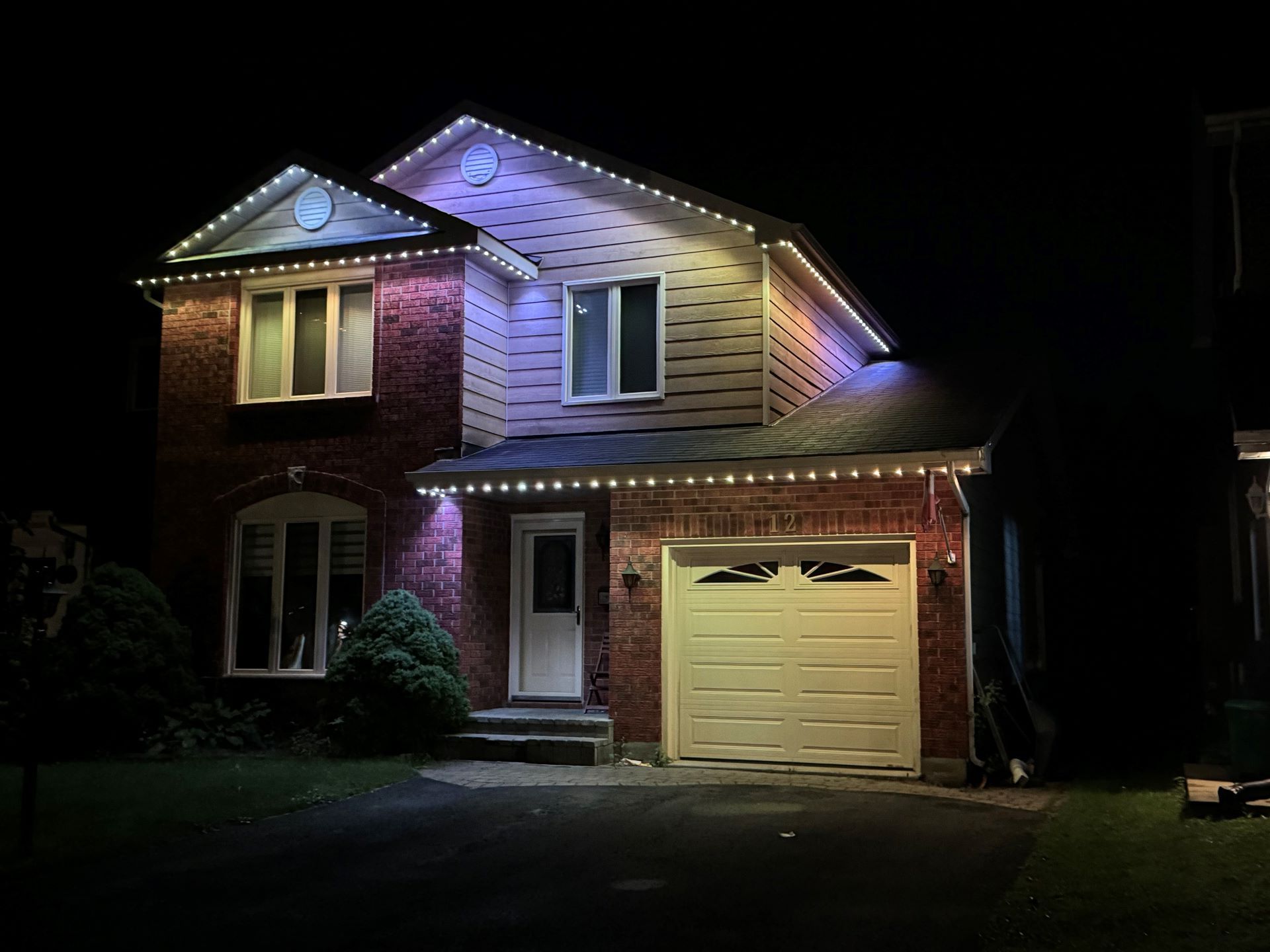 A house with christmas lights on it is lit up at night.