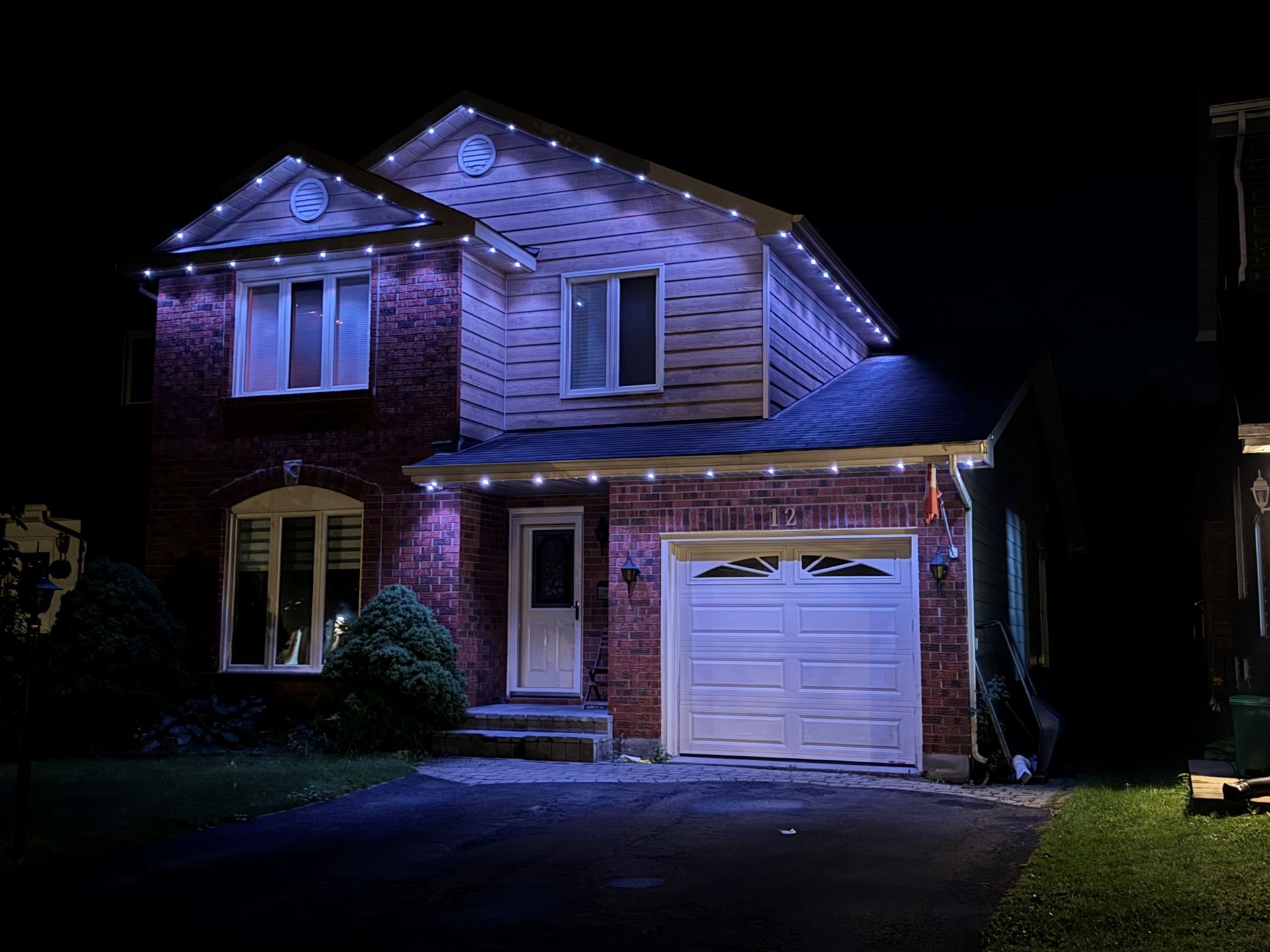 A house with christmas lights on it is lit up at night.