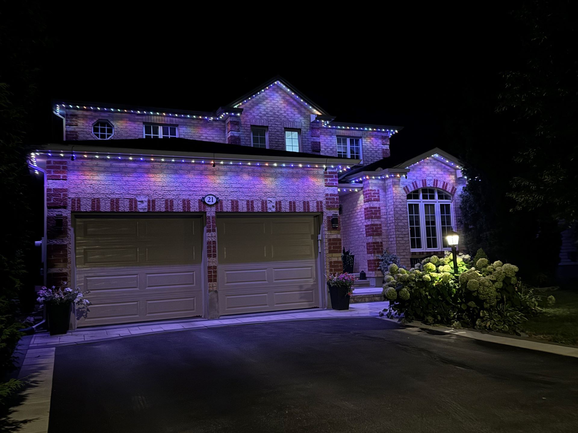 A large house with purple lights on it is lit up at night.