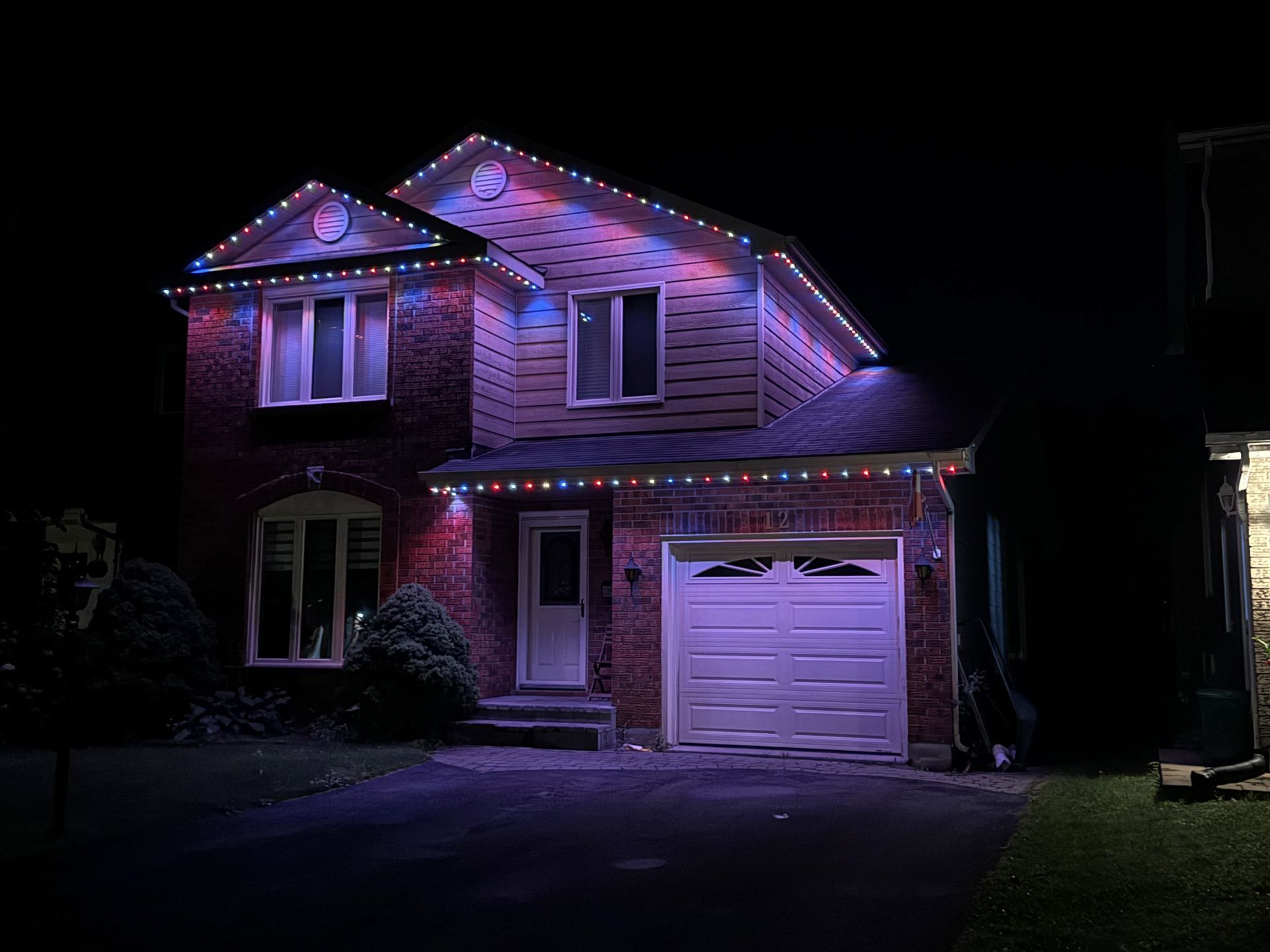 A house with christmas lights on it is lit up at night.