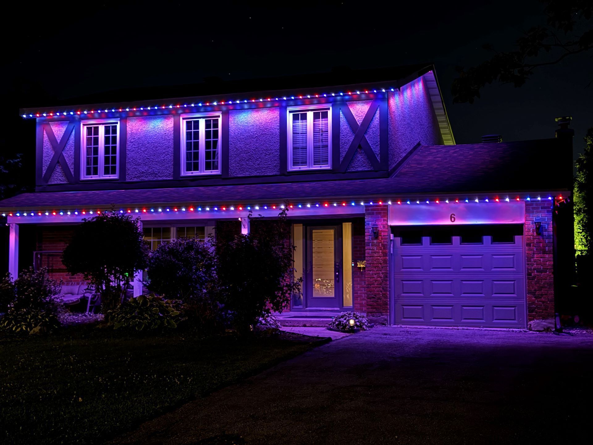 A house is lit up with purple and red christmas lights.