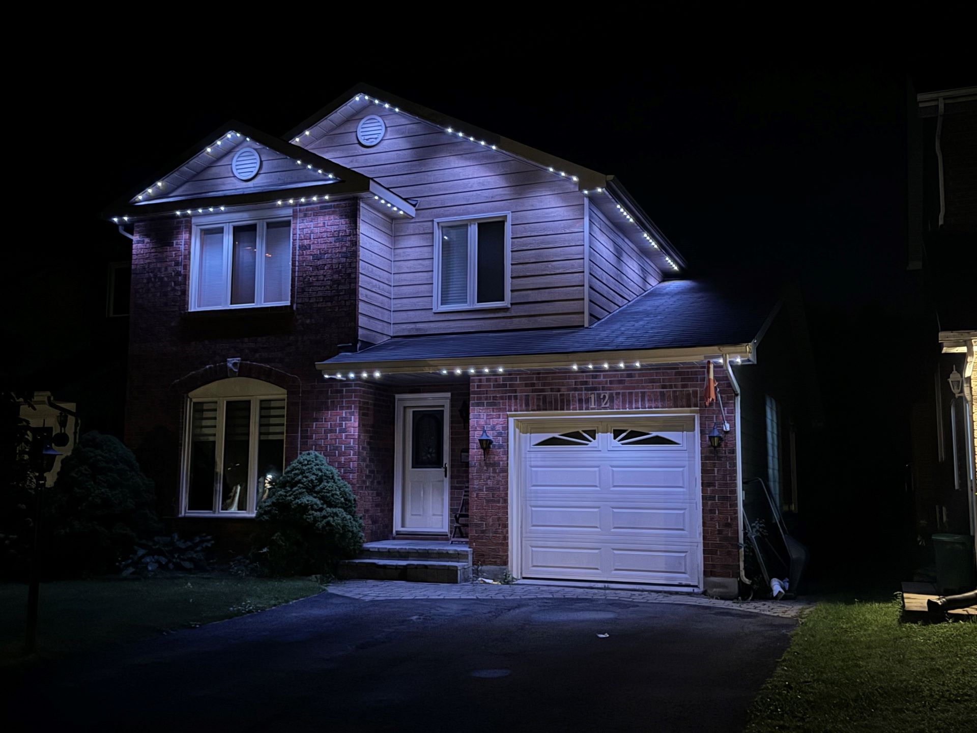 A house with christmas lights on it is lit up at night.