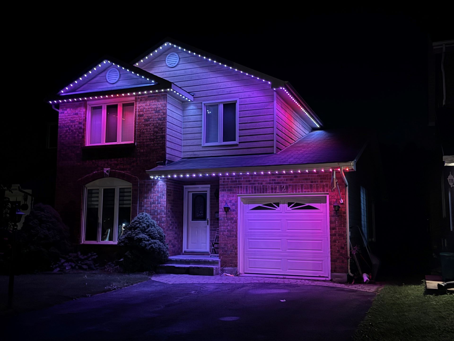 A house is lit up with purple and pink lights at night.