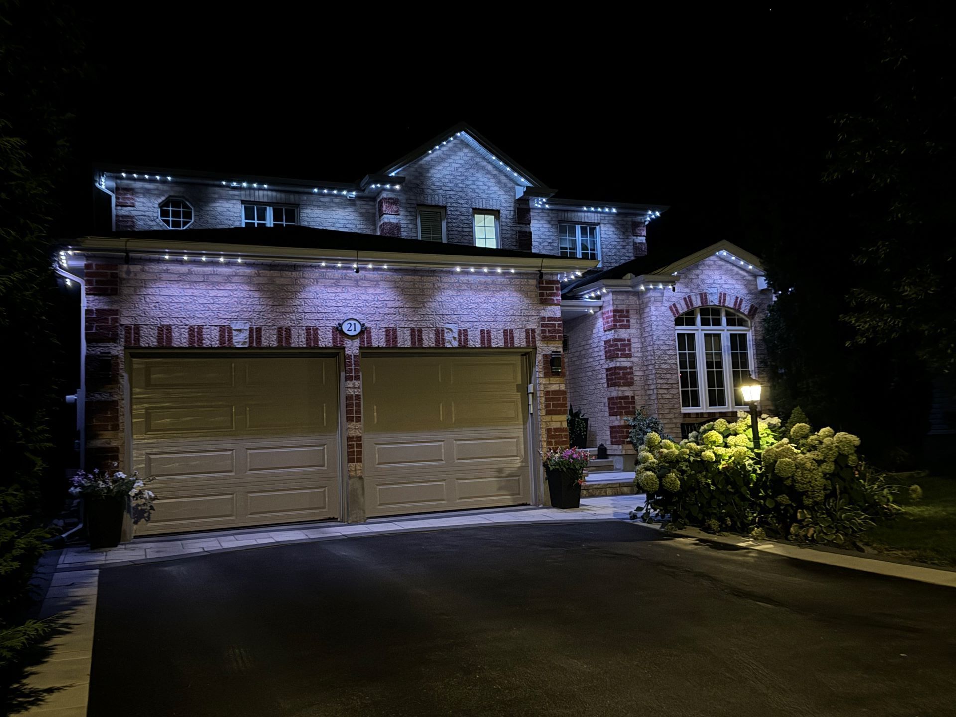 A house with a garage and a driveway is lit up at night.