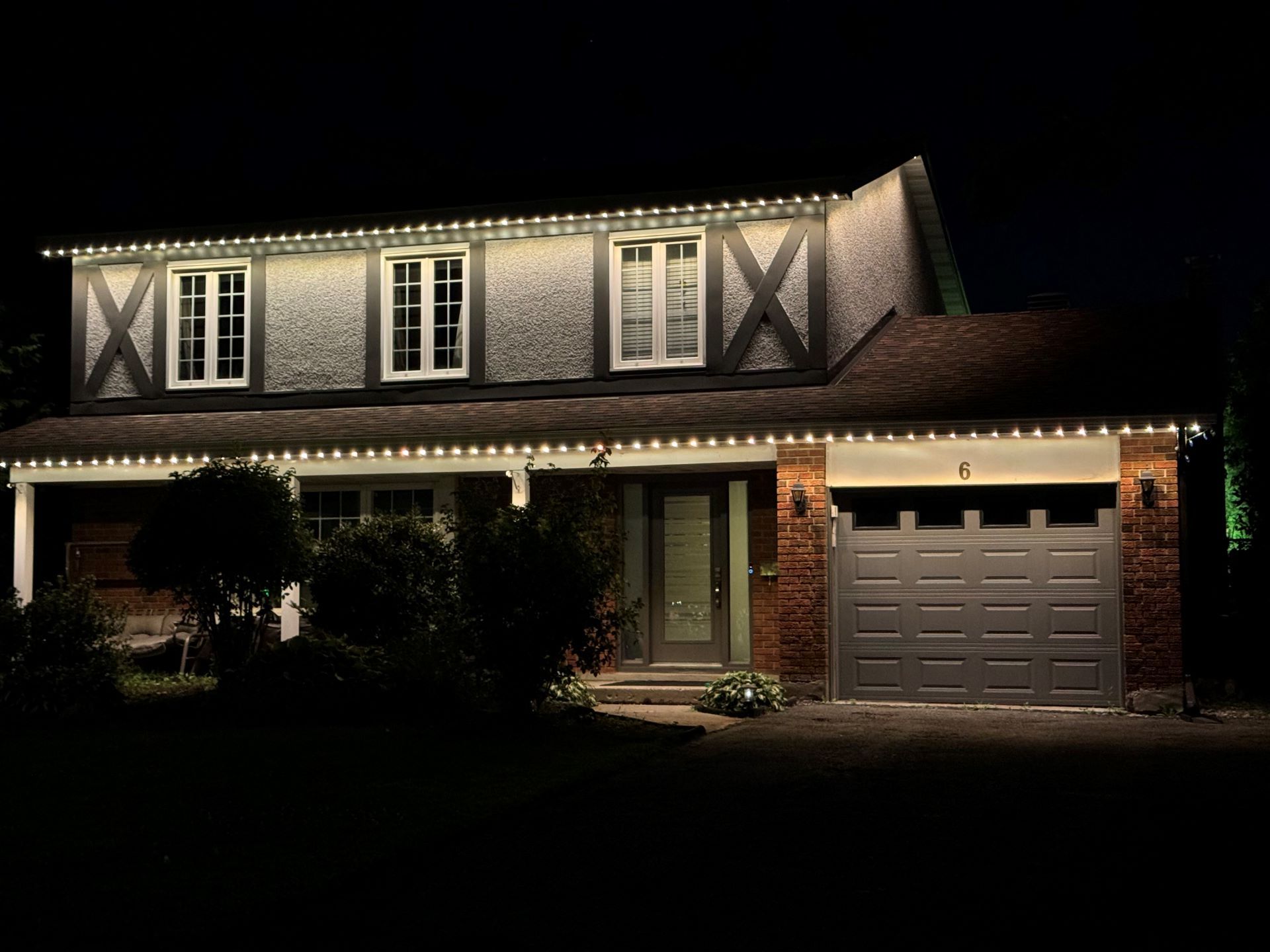 A house with christmas lights on it is lit up at night.