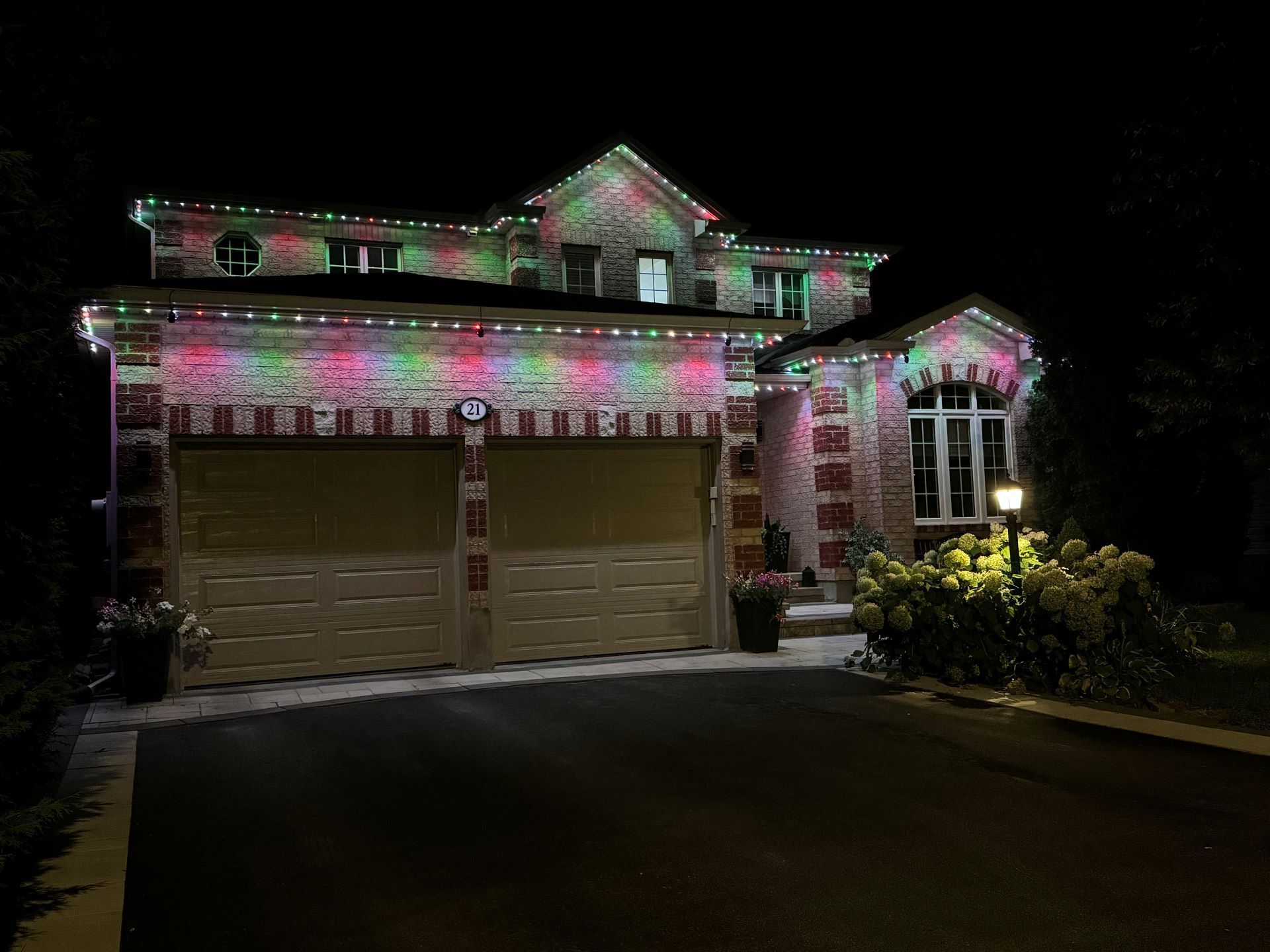 A large house is decorated with christmas lights at night.