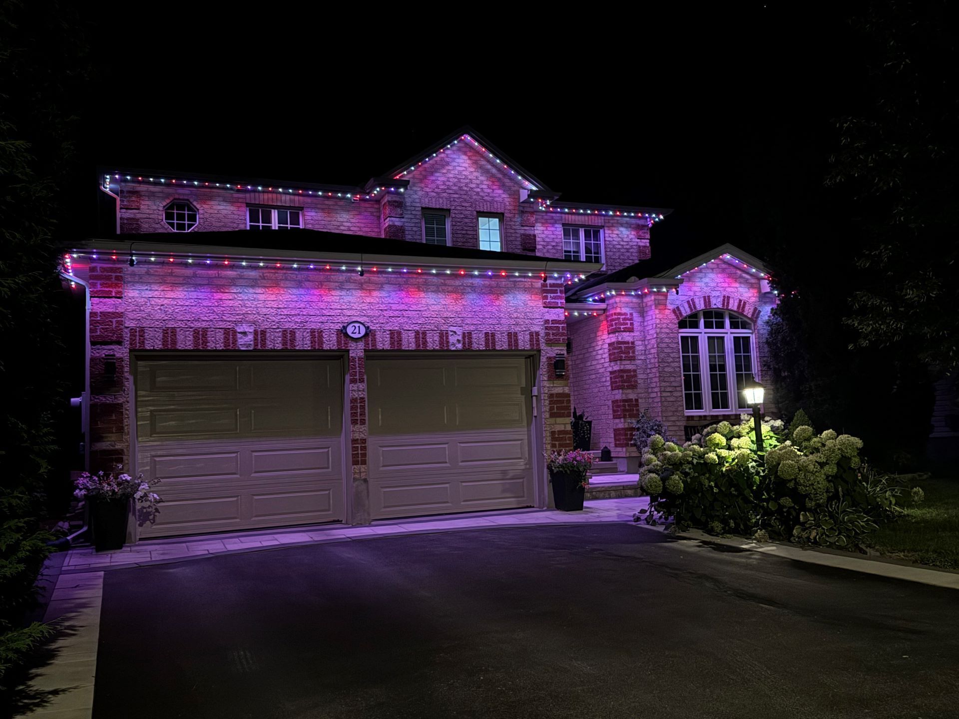 A house with purple lights on it is lit up at night.