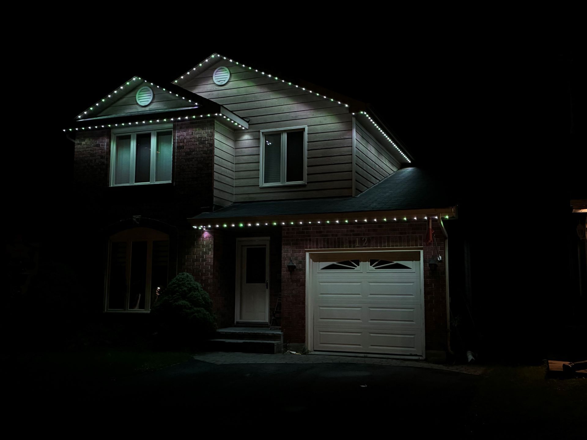 A house with christmas lights on it is lit up at night.