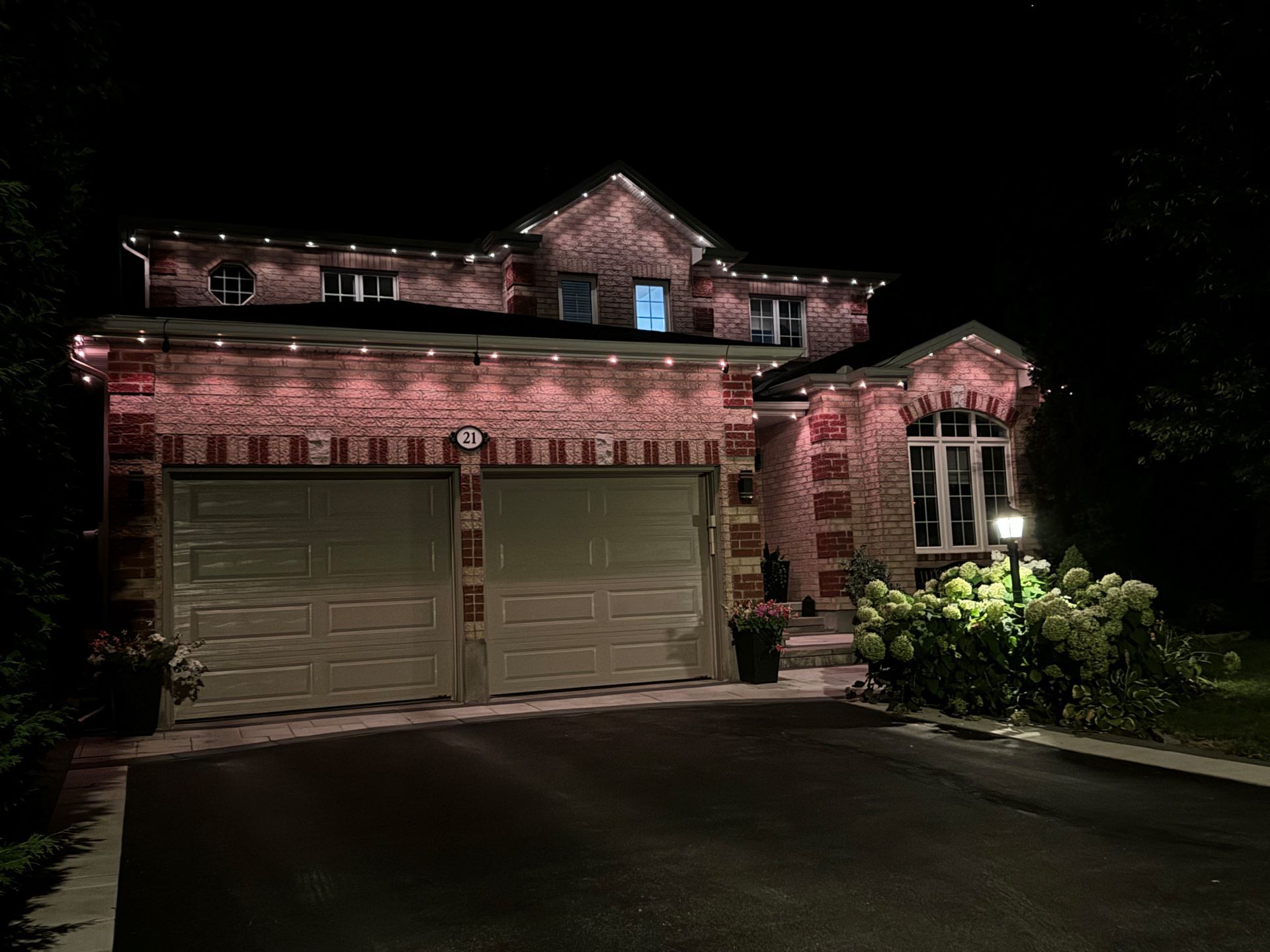 A large brick house with christmas lights on it is lit up at night.