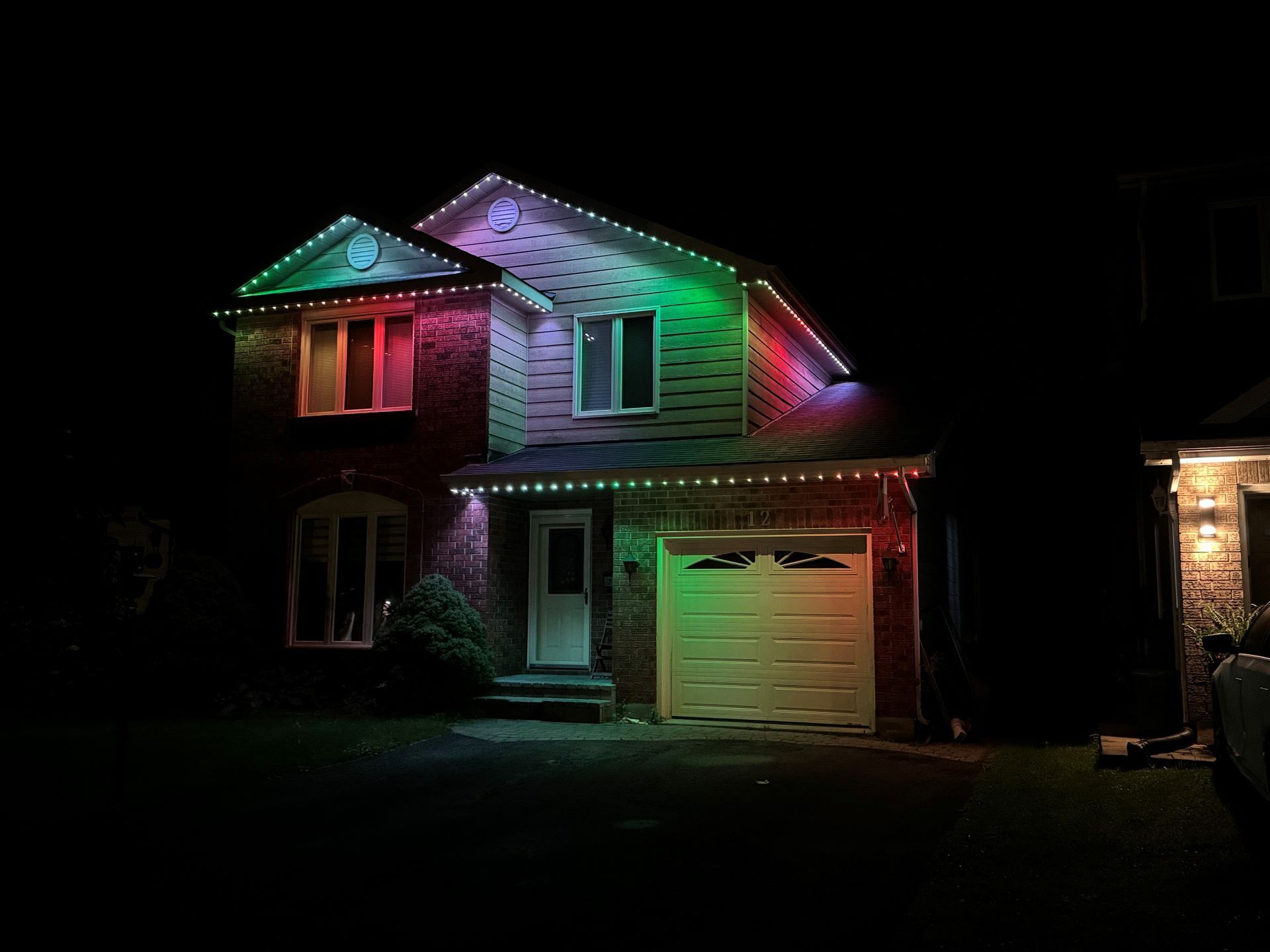 A house with christmas lights on it is lit up at night.