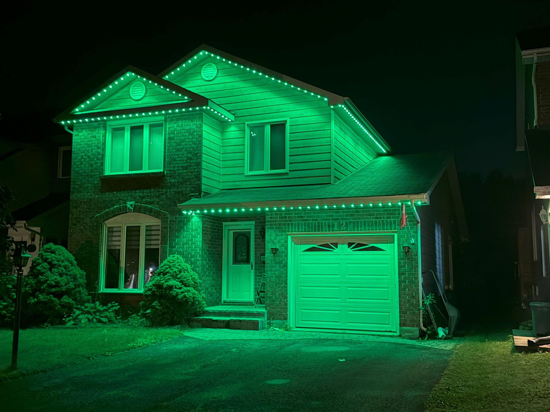 A house is lit up with green lights at night.