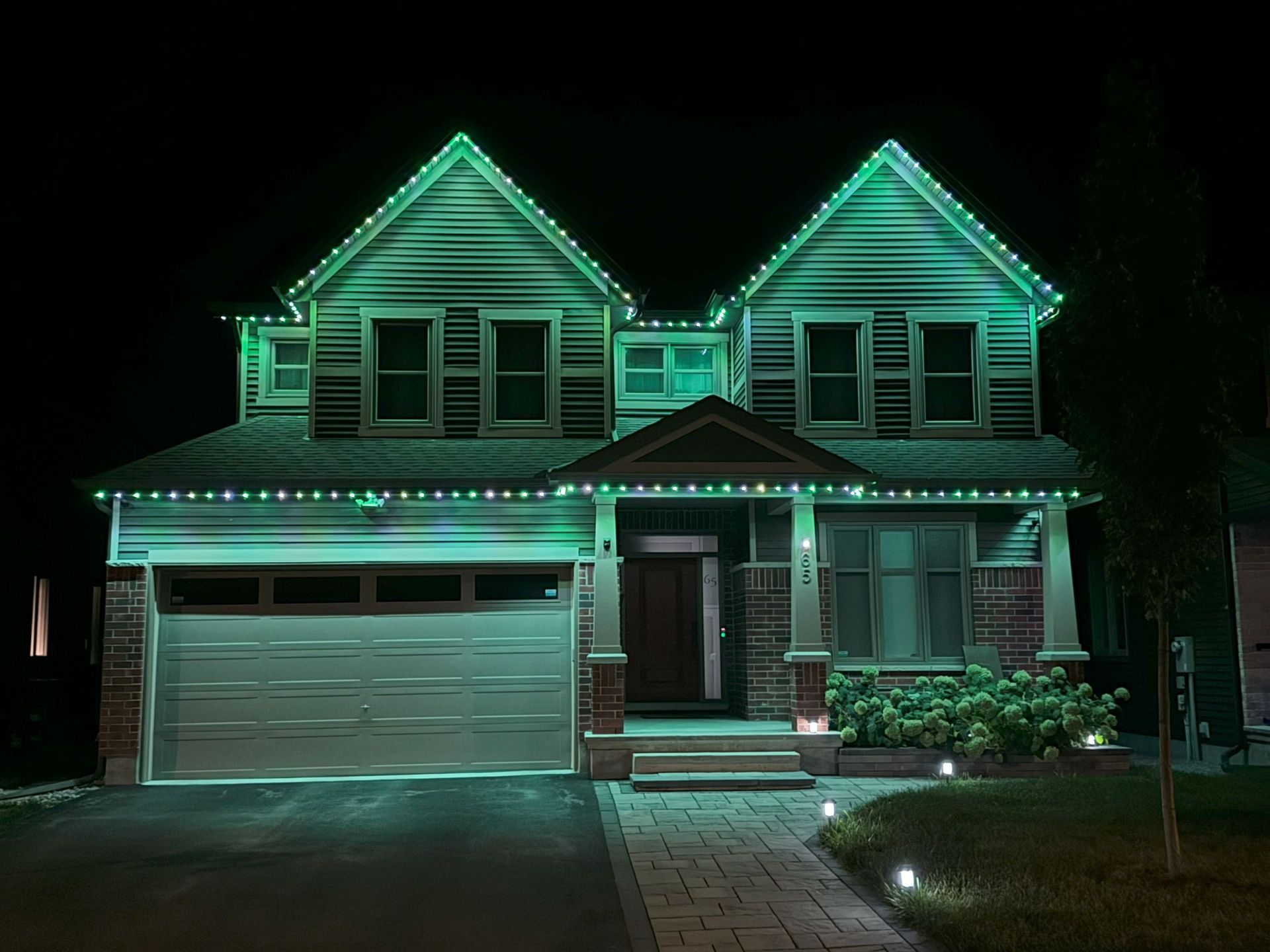A house is lit up with green christmas lights at night.