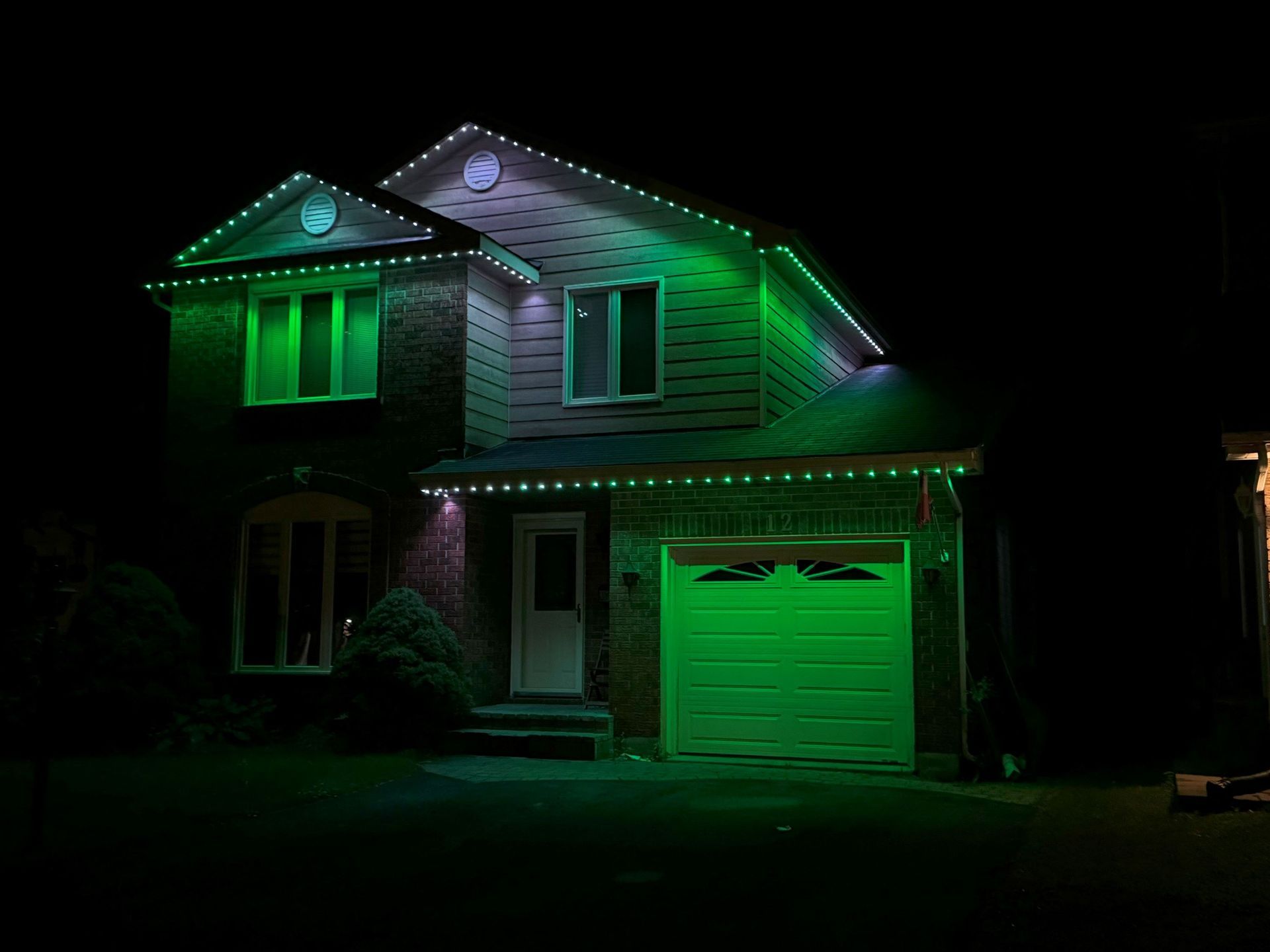 A house with green lights on it is lit up at night.
