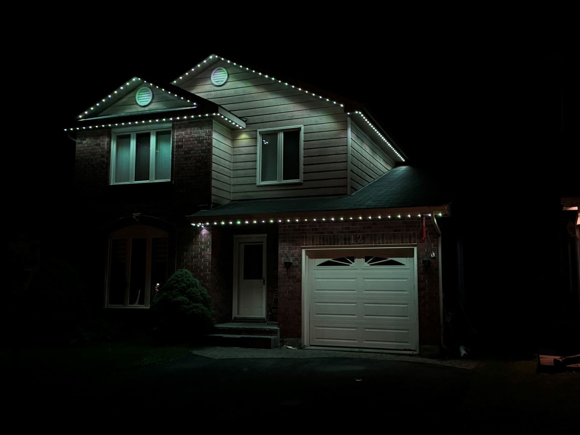 A house with christmas lights on it is lit up at night.