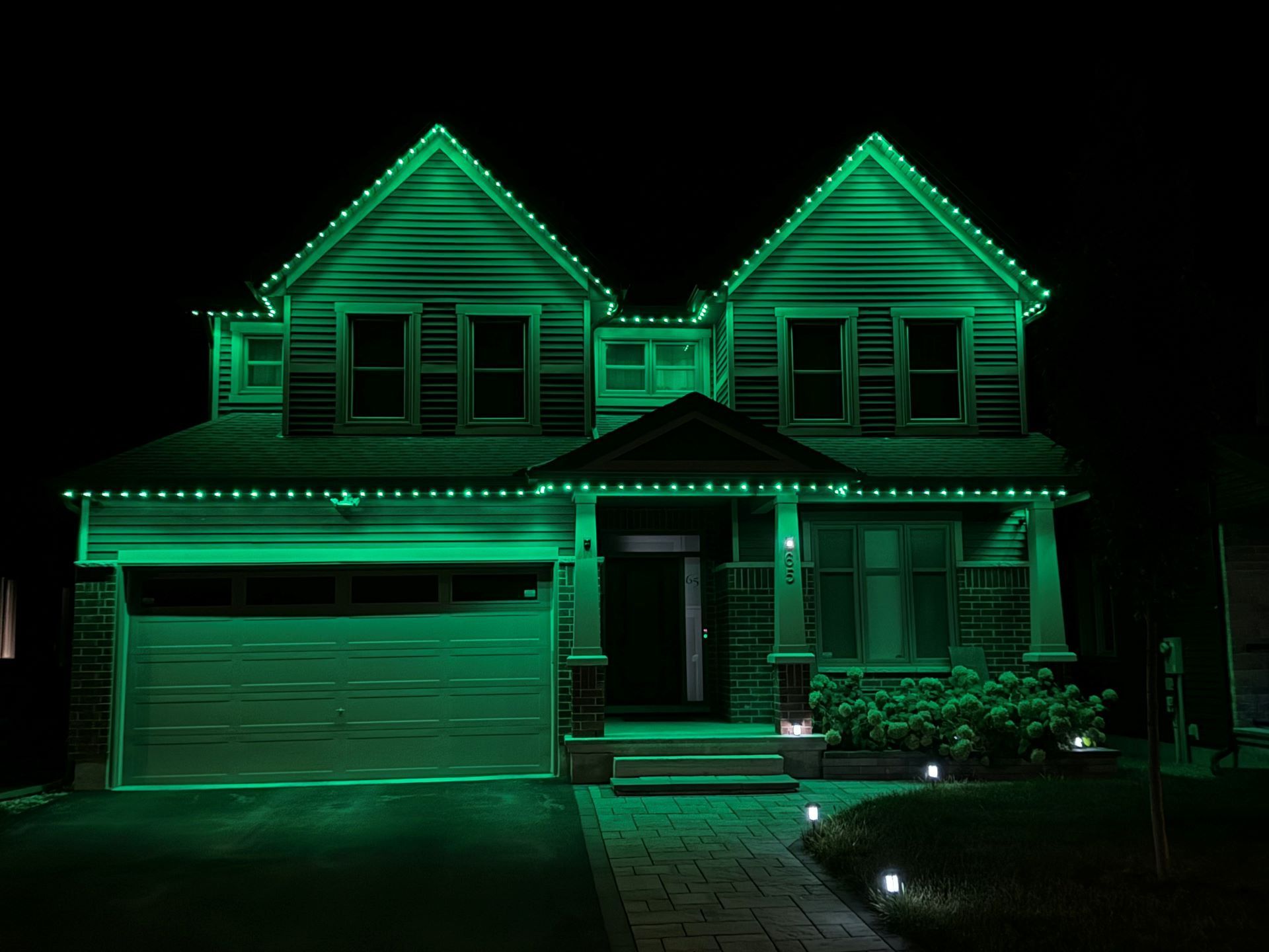 A house is lit up with green lights at night.