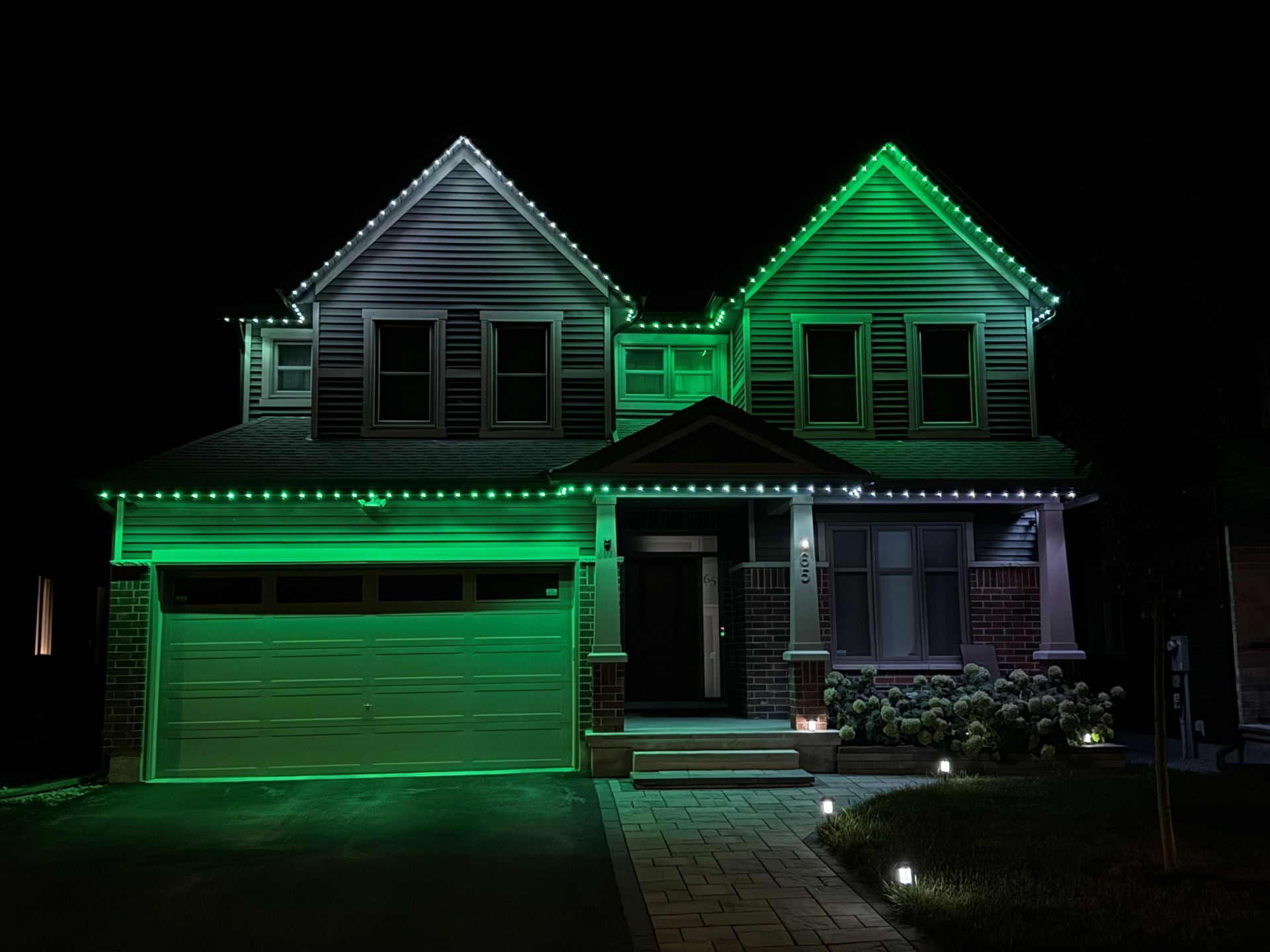 A house is lit up with green lights at night.