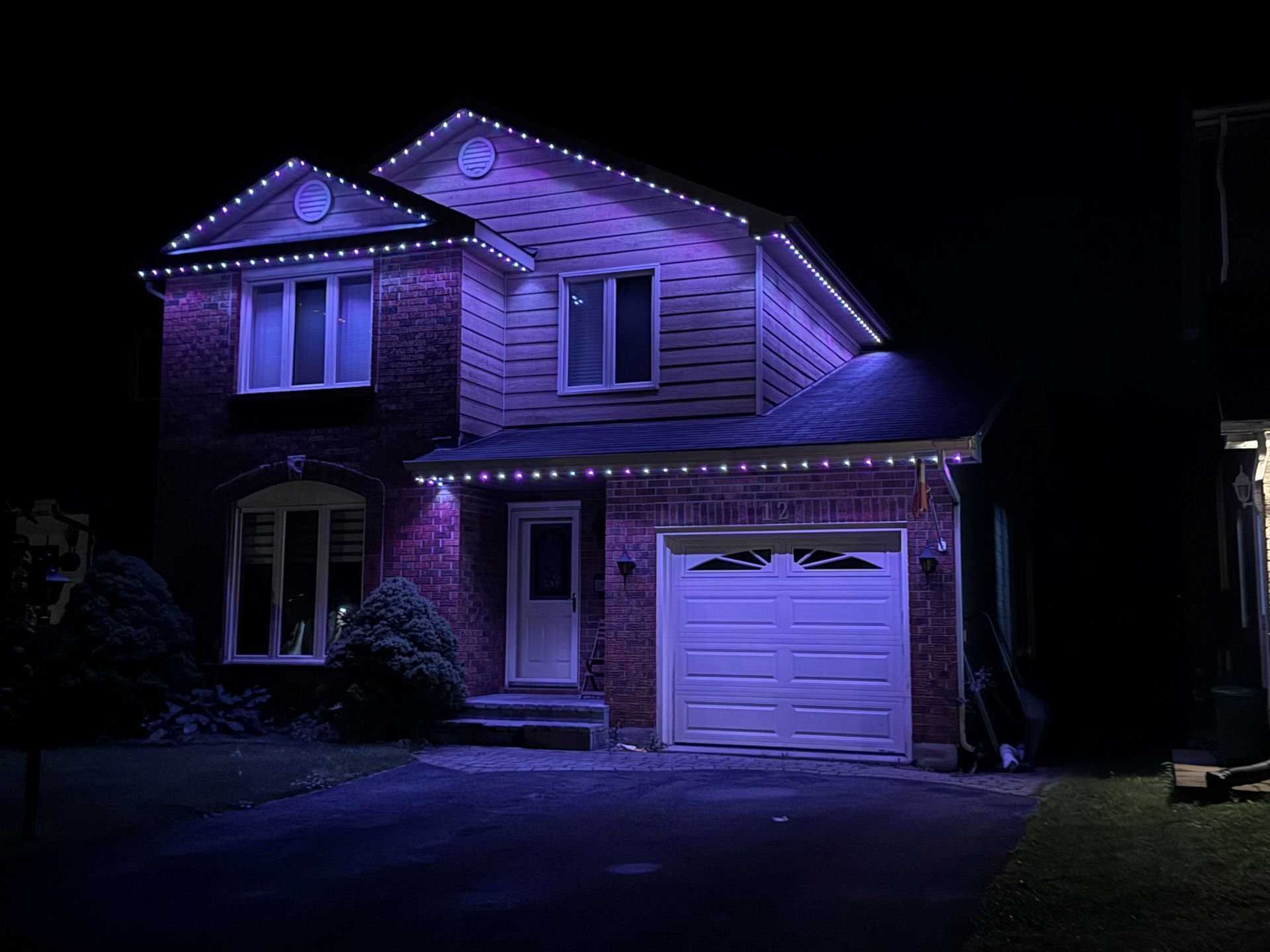 A house with purple lights on it is lit up at night.