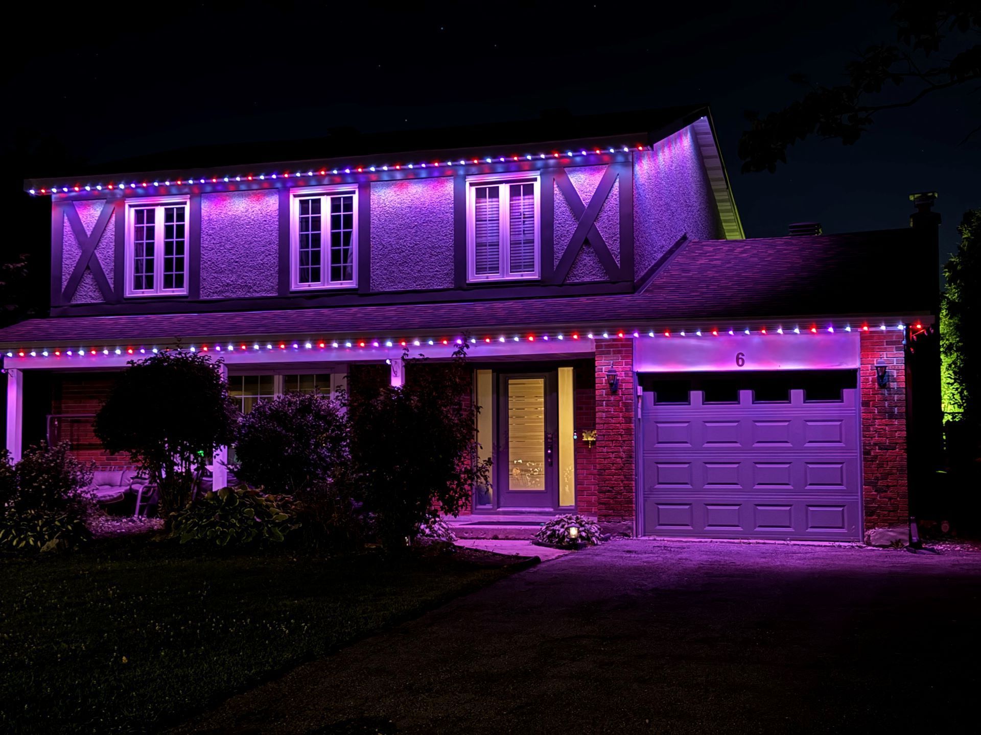 A house is lit up with purple and red christmas lights