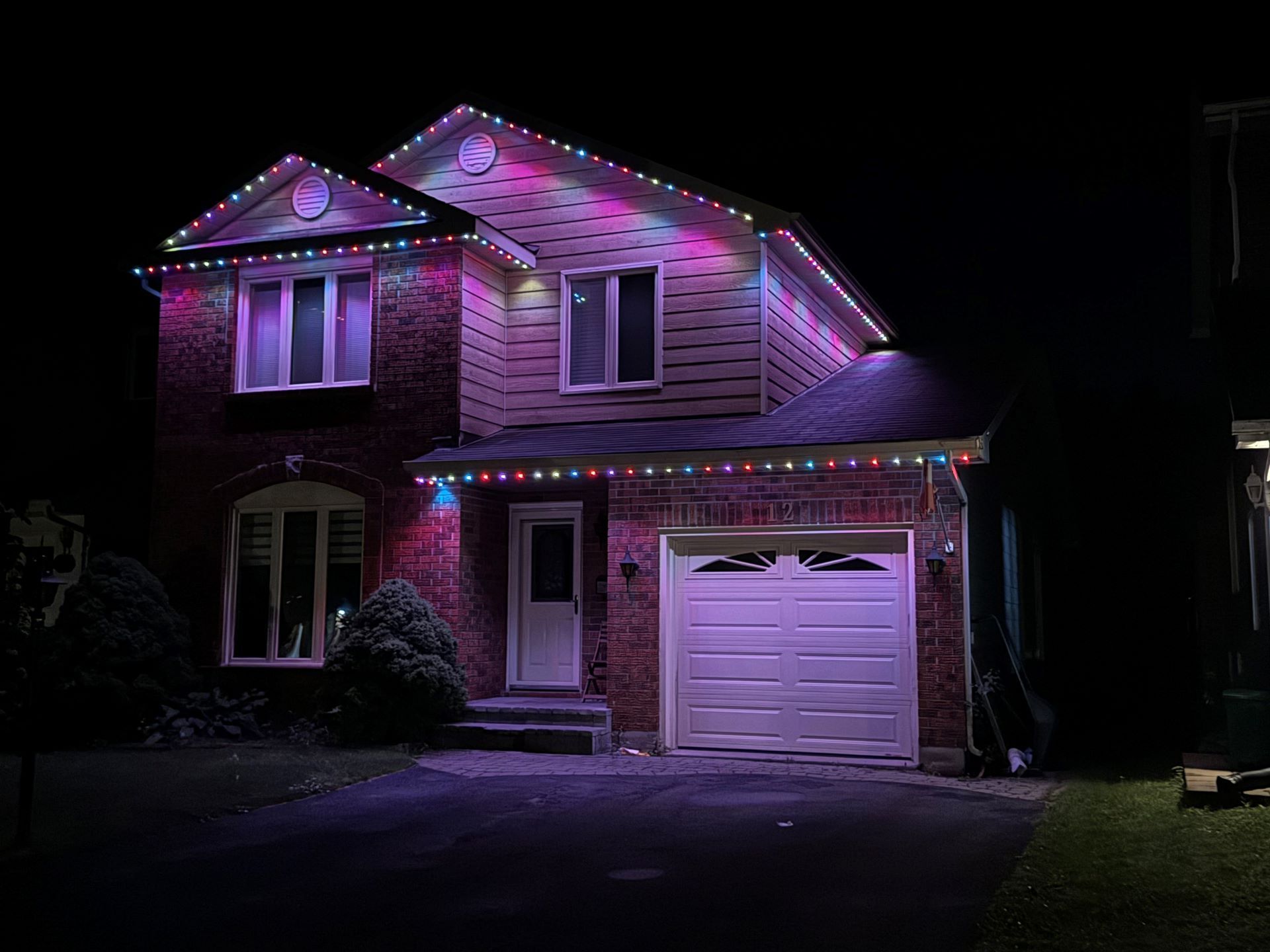A house with christmas lights on it is lit up at night.