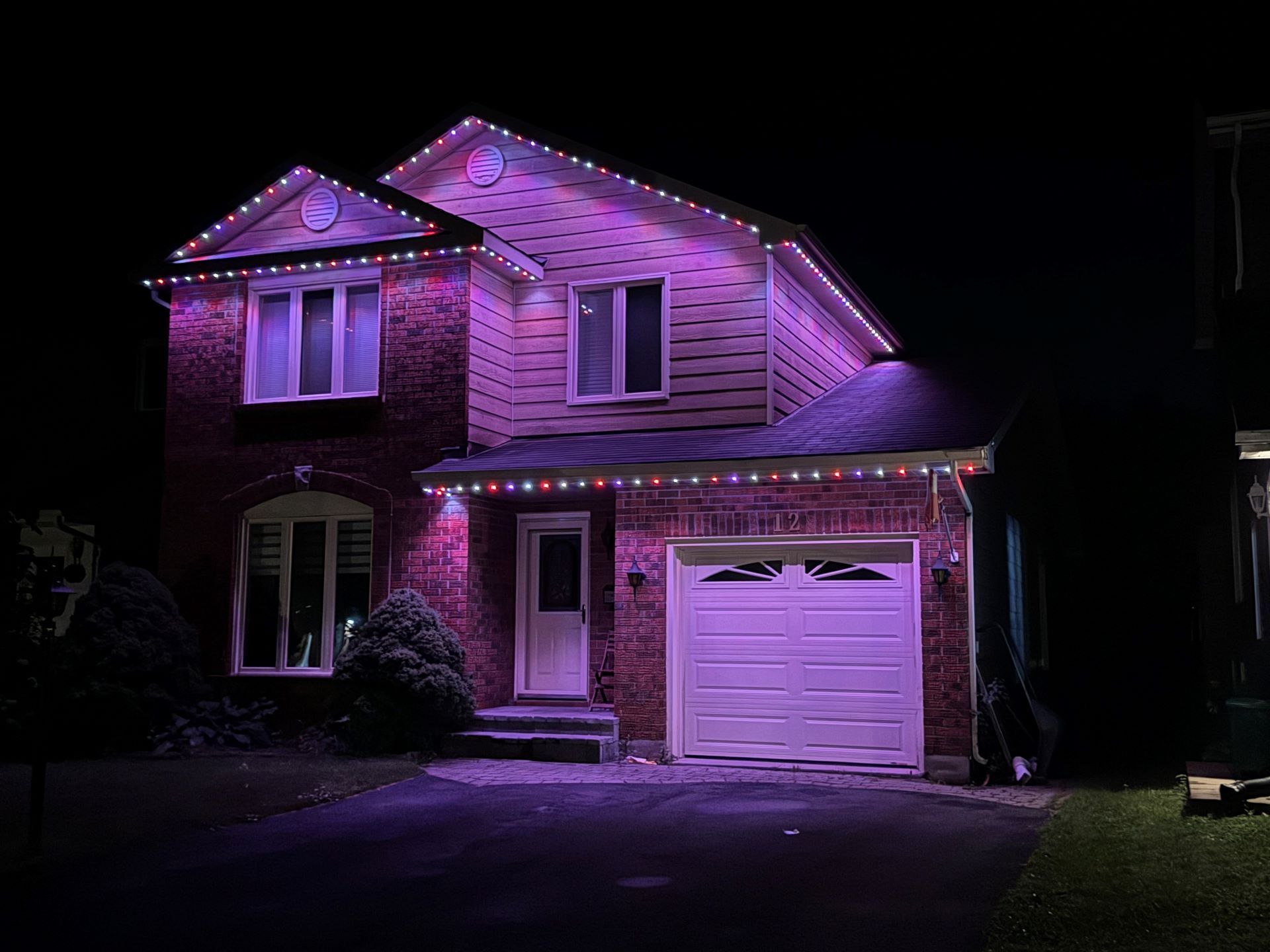 A house with christmas lights on it is lit up at night.