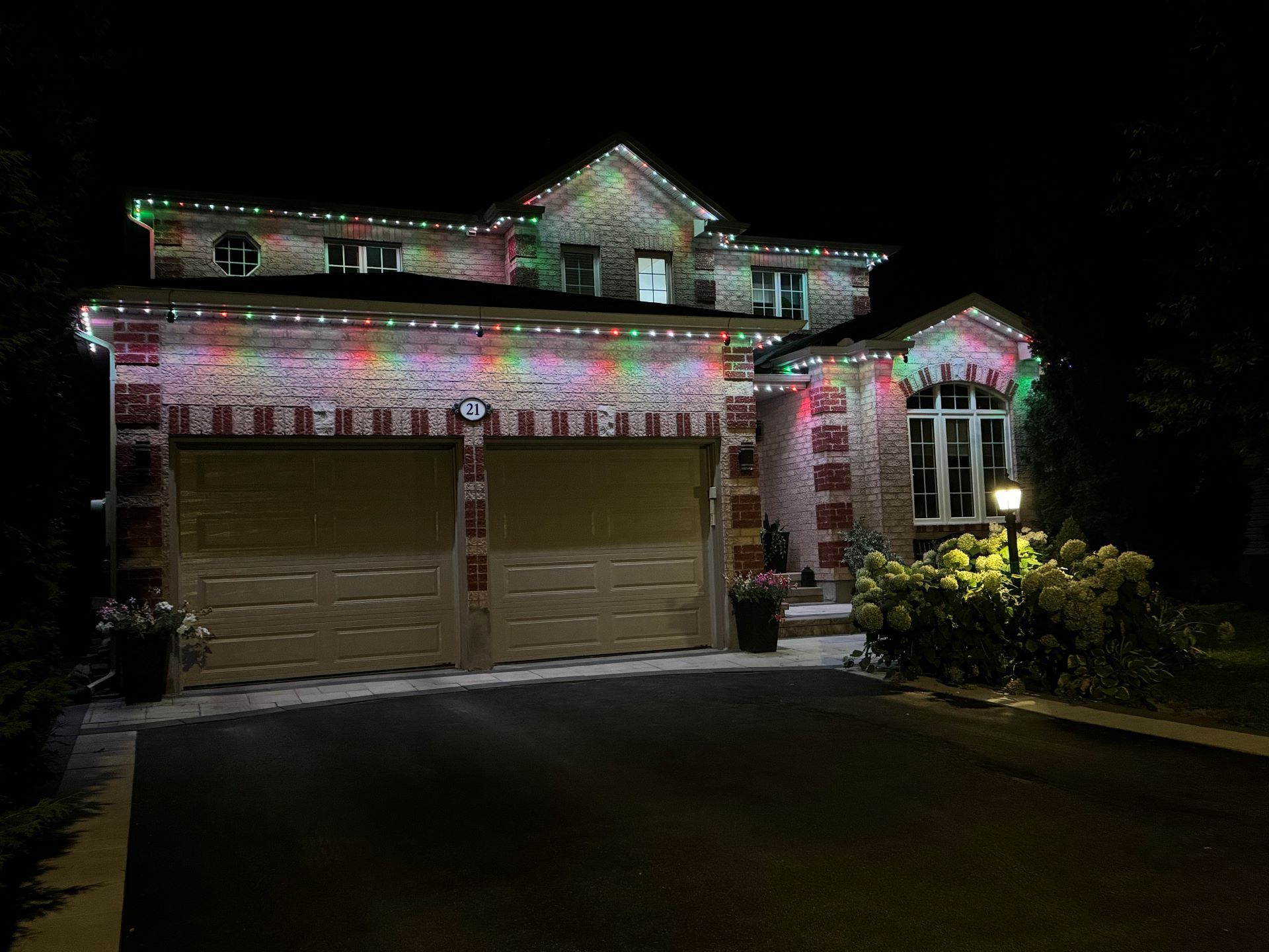 A large house is decorated with christmas lights at night.