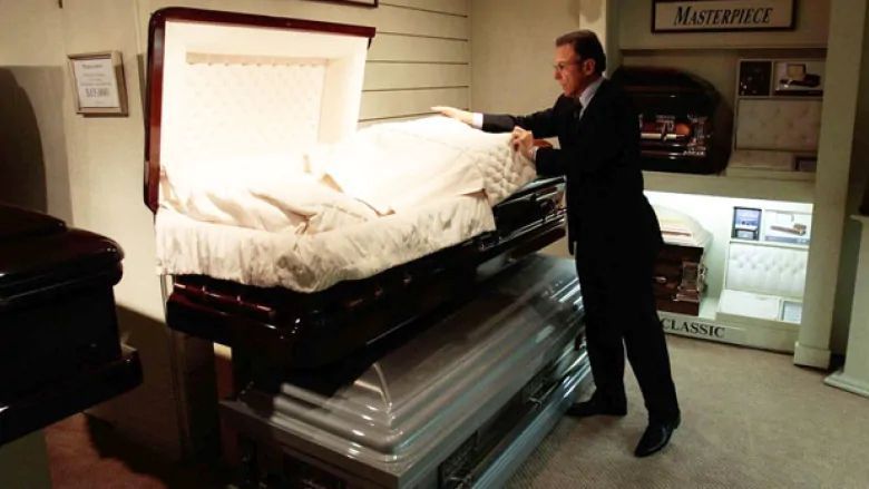 a man in a suit is opening a coffin in a funeral home .