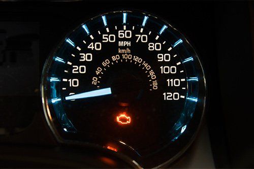 A close up of a speedometer with a red light on it