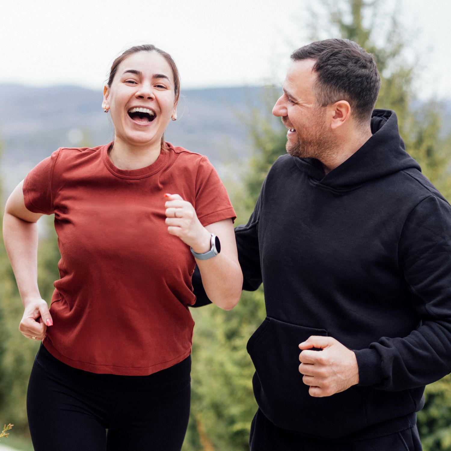 A man and a woman are laughing together while standing next to each other.