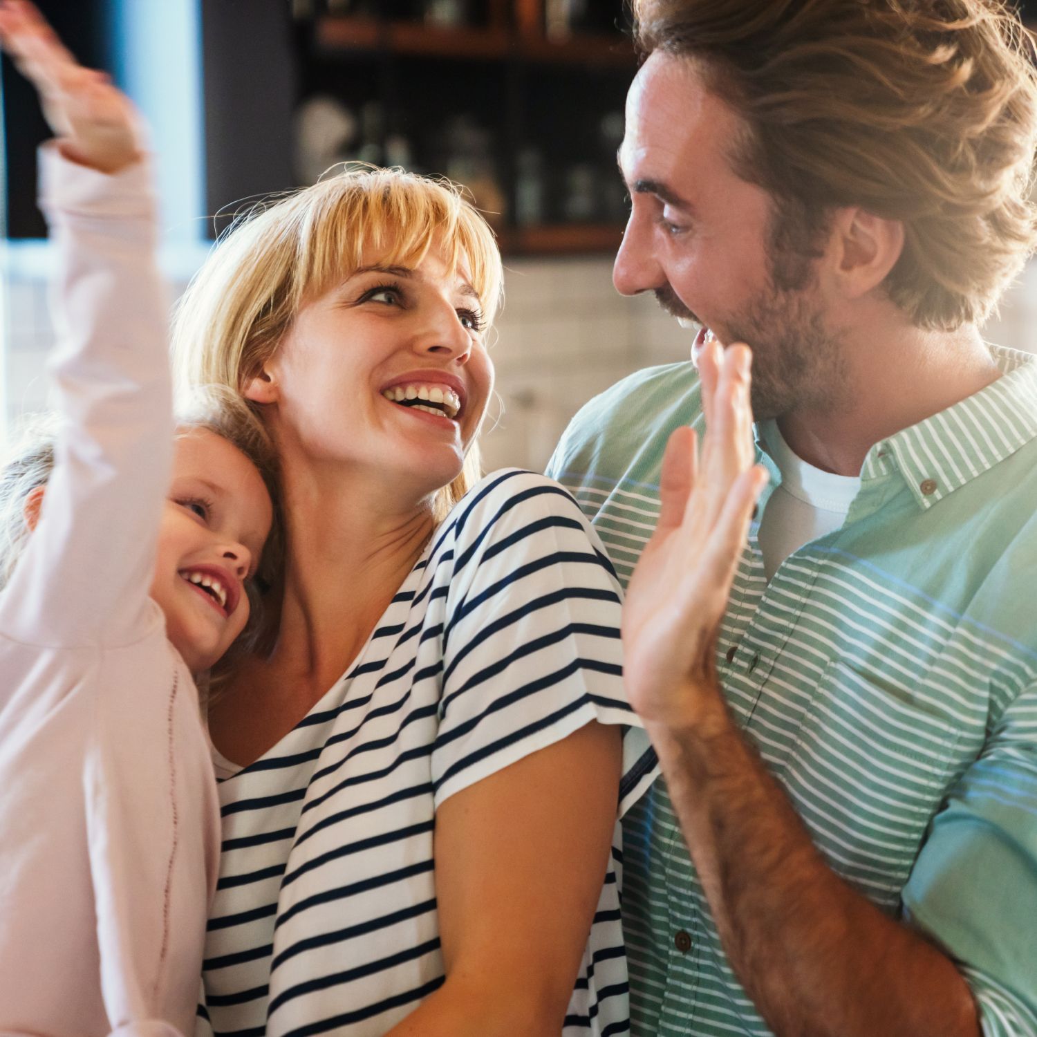 A man and woman are holding a little girl who is reaching up towards the sky.