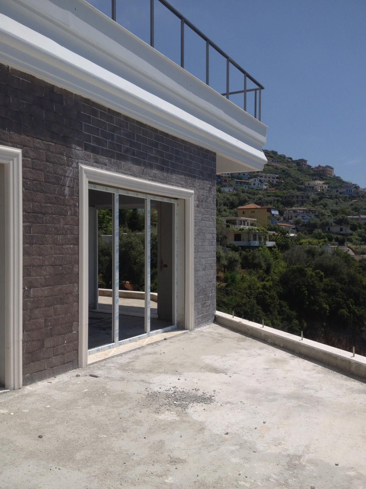 Prua di uno yacht grigio con corrimano in acciaio inossidabile, ancora e ponte in legno.