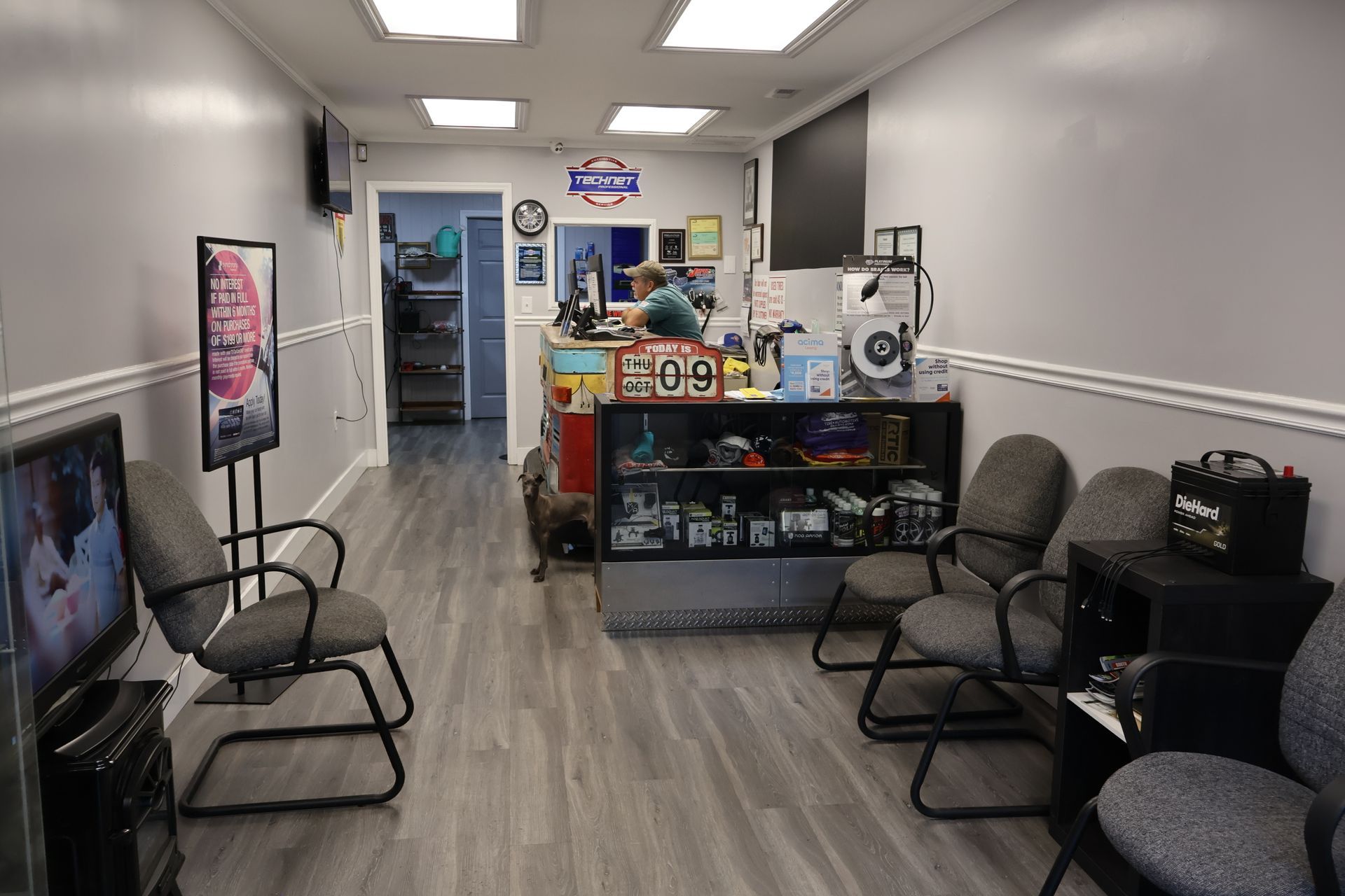 Small dog lying on wooden floor in front of a truck-themed reception desk.| S&S Tire Inc & Automotive
