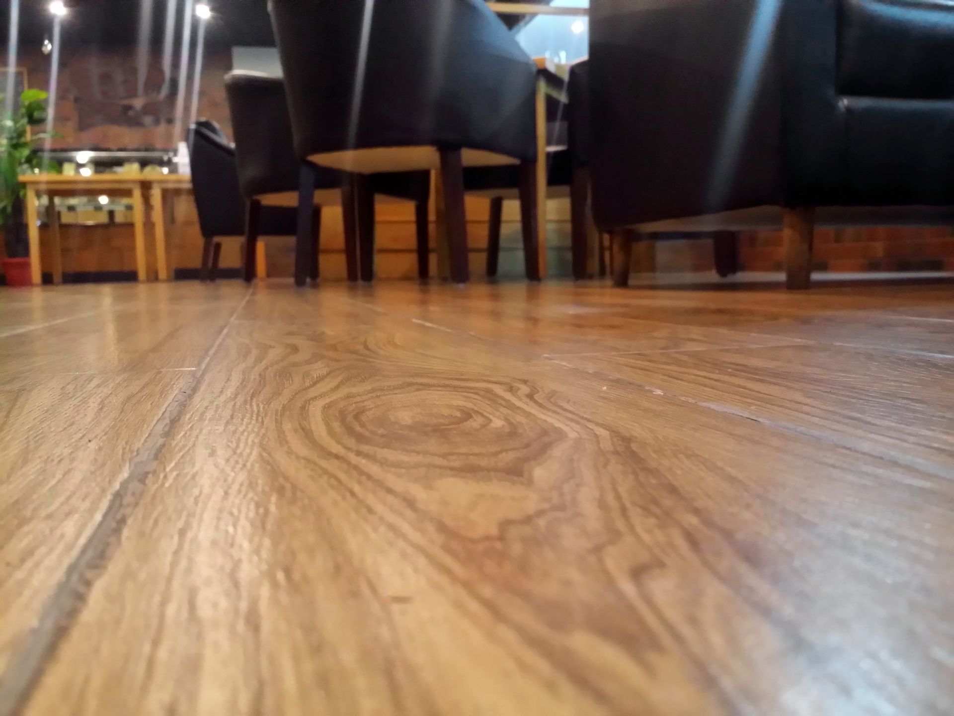 A wooden floor with chairs and tables in the background
