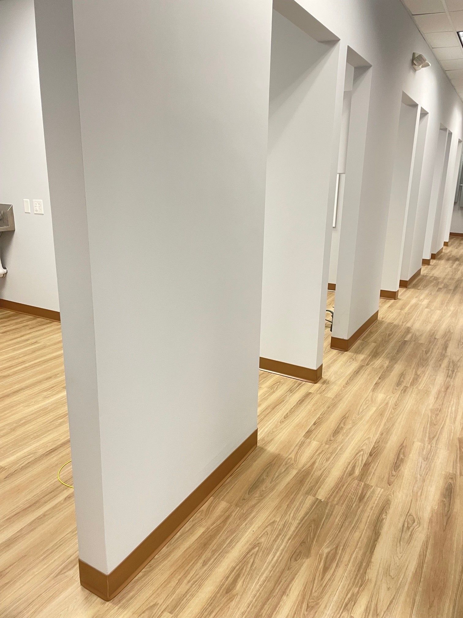 A long hallway with wooden floors and white walls in a dental office.