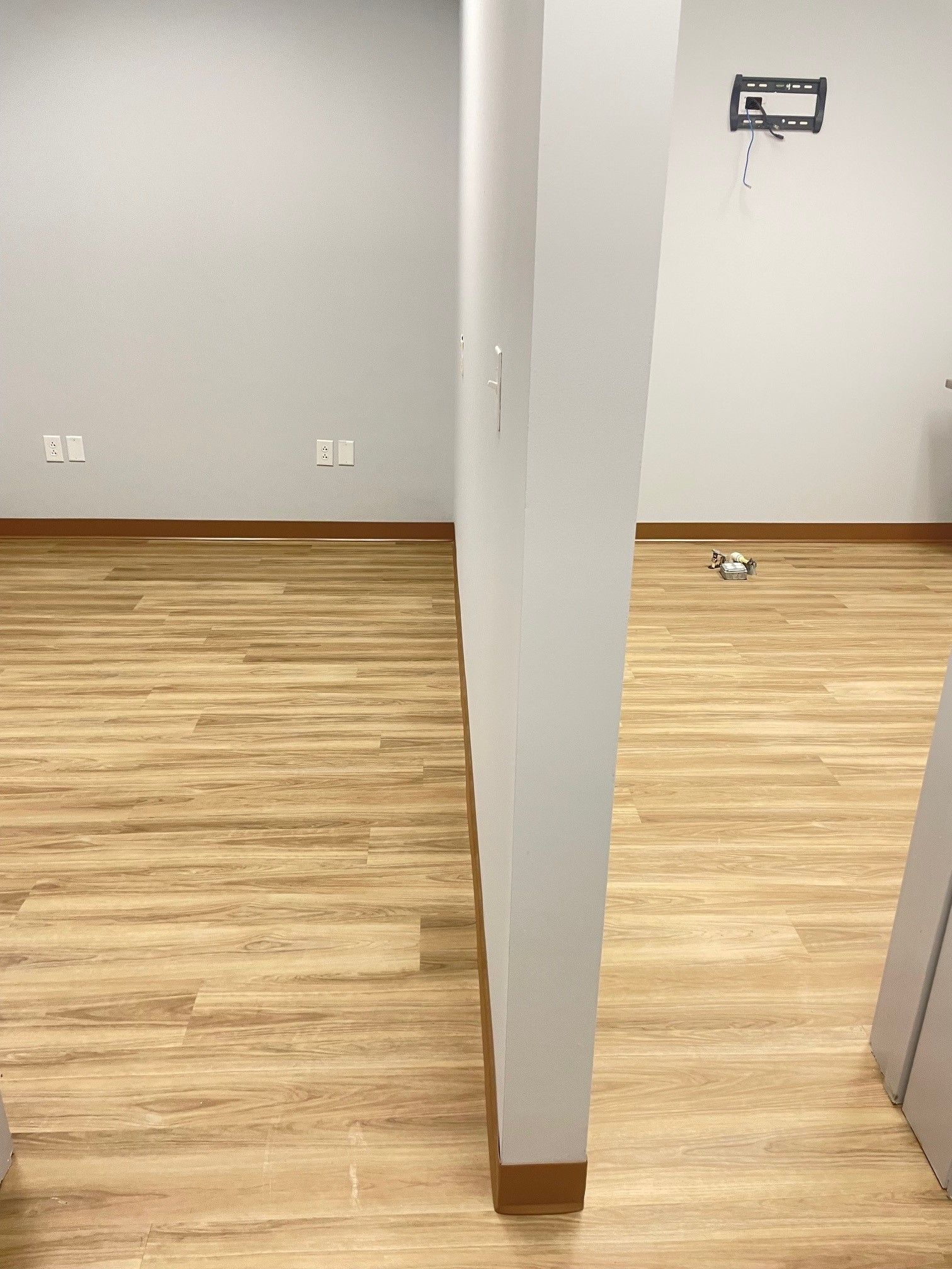 A room with a wooden floor and a white wall.