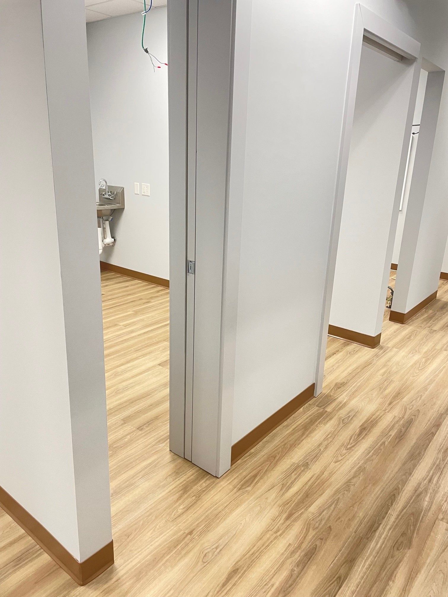 A hallway in a dental office with wooden floors and white walls.