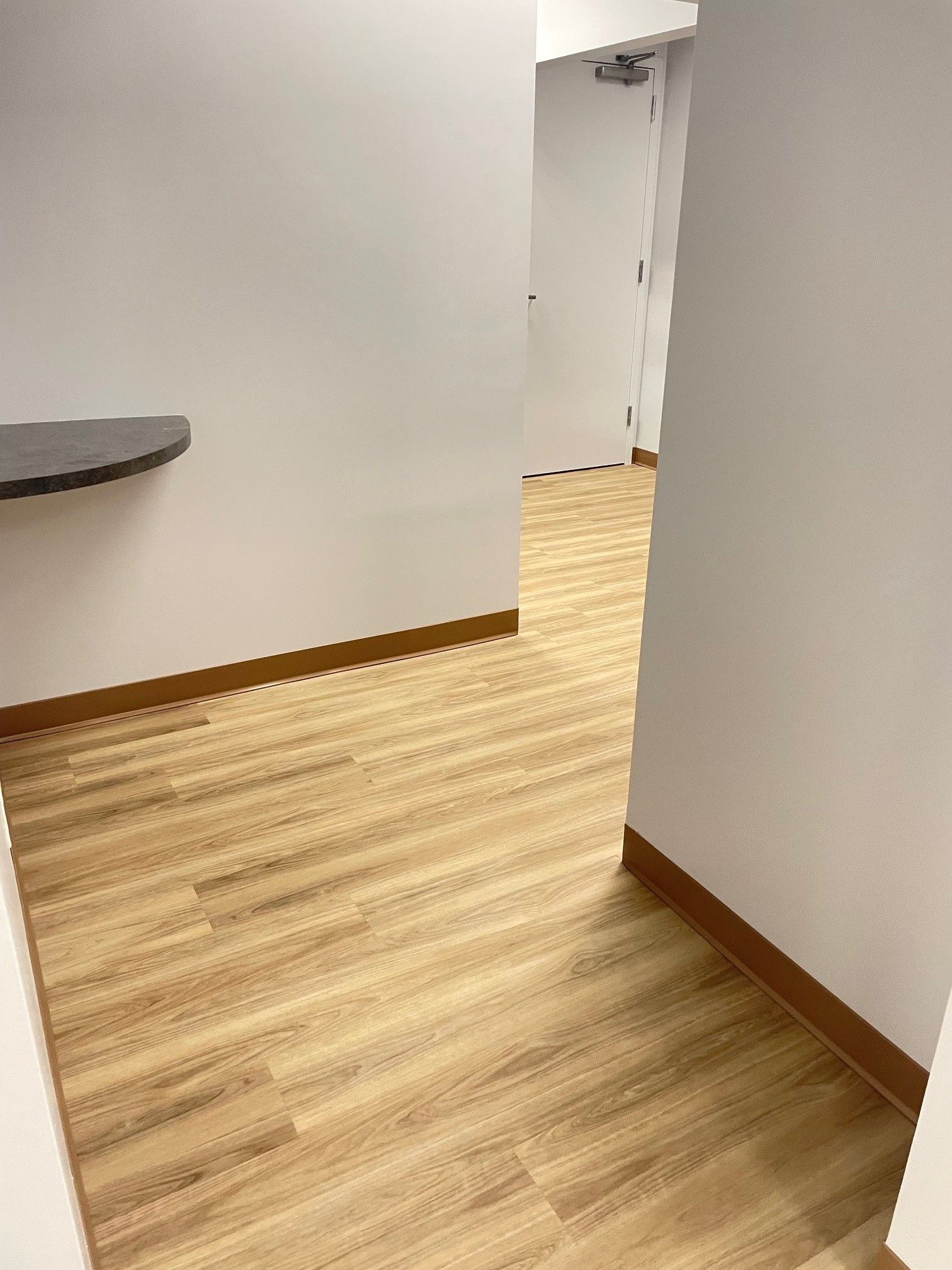 A hallway with a wooden floor and white walls.