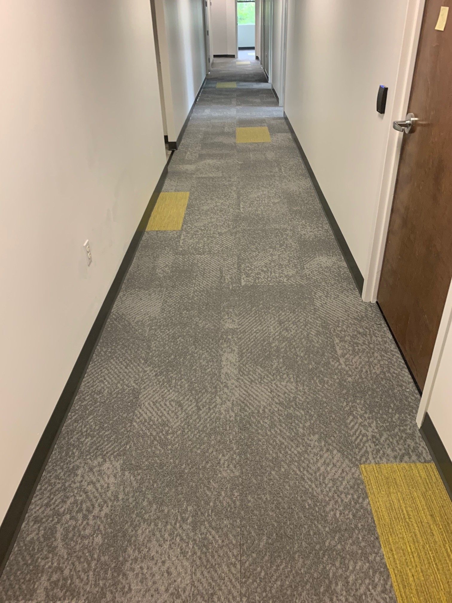 A long hallway with a carpeted floor and a door.