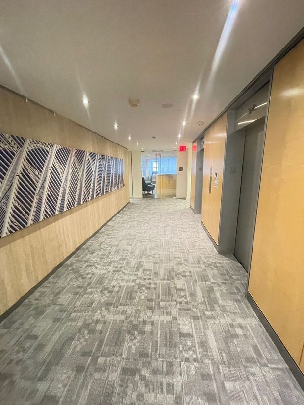 A long hallway in an office building with a painting on the wall.