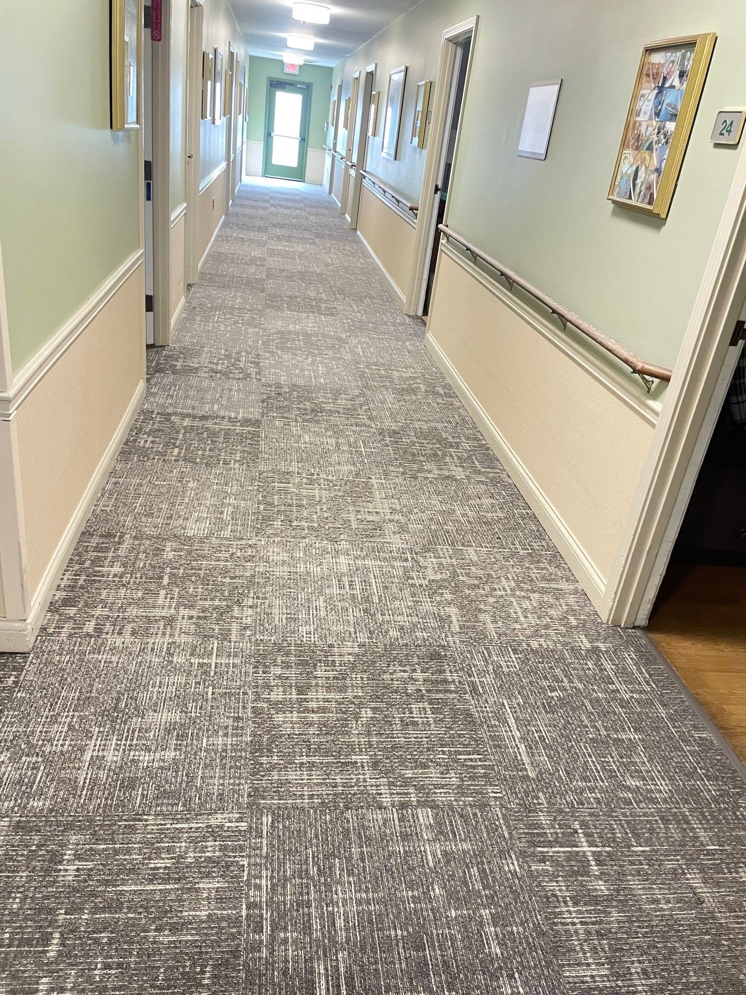 A long hallway with a carpeted floor in a nursing home.